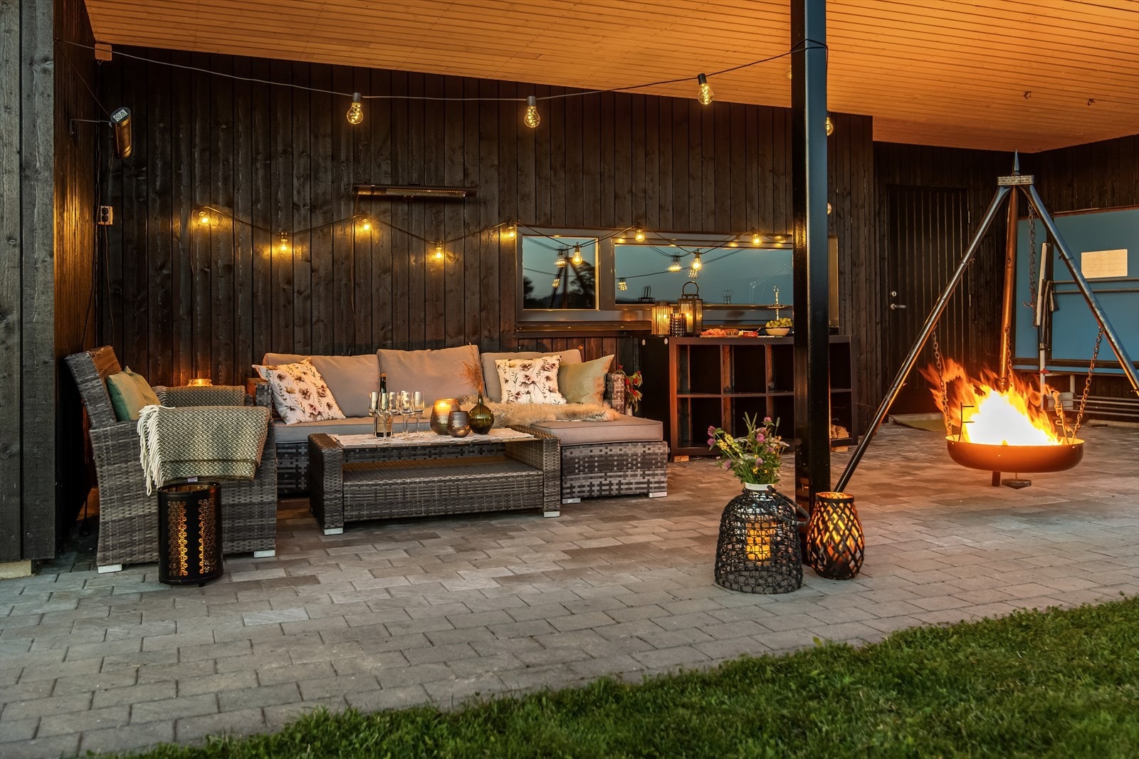Fra stuen i underetasjen kommer man ut i en steinlagt, overbygget uteplass som flyter over i plenareal. Her kan man nyte solnedganger med bålpanne og hyggelige selskap! Galleribilde