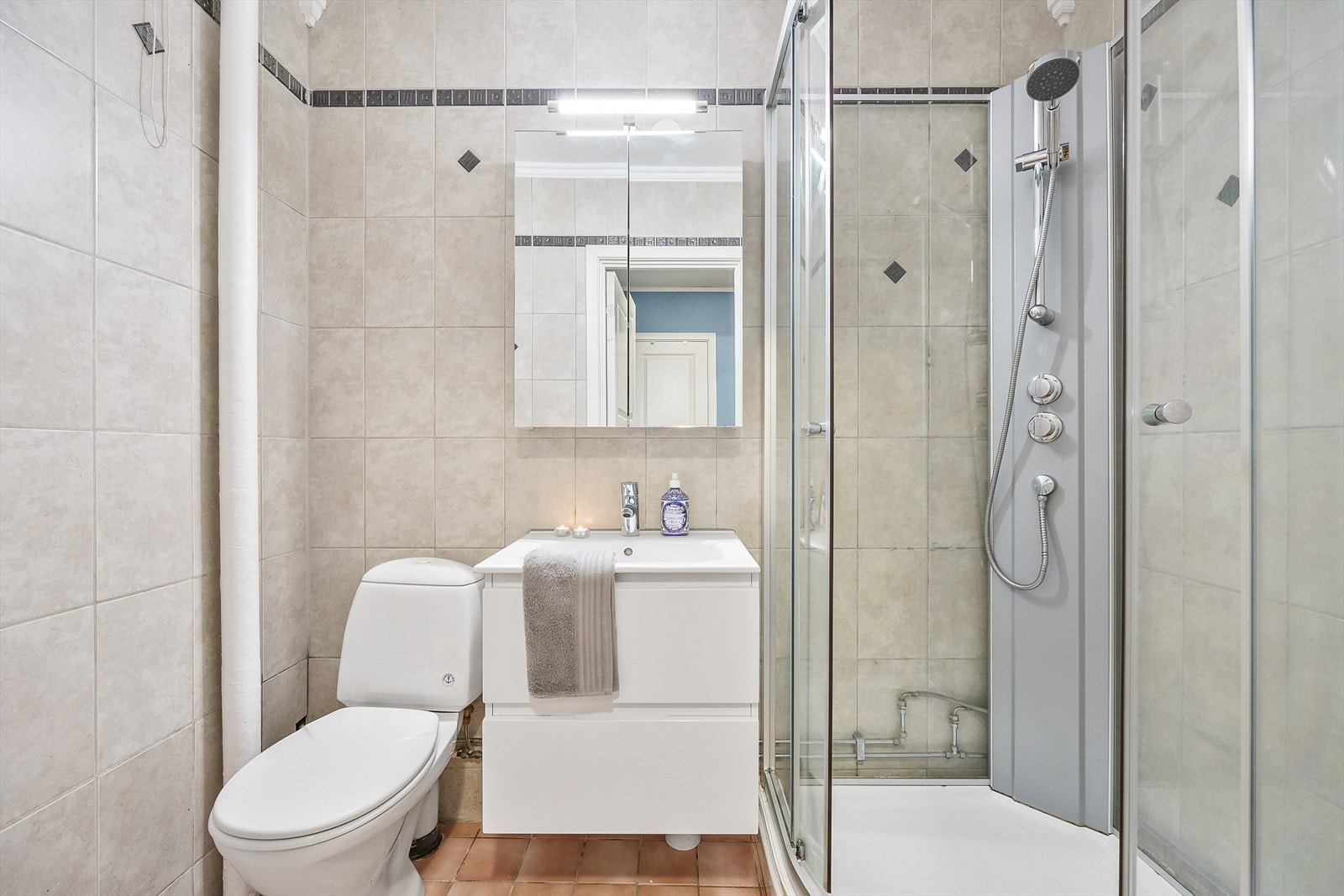 Pent flislagt bad. Badet er utstyrt med dusjkabinett, gulvstående wc og servantinnredning med skuffer og overskap. Galleribilde