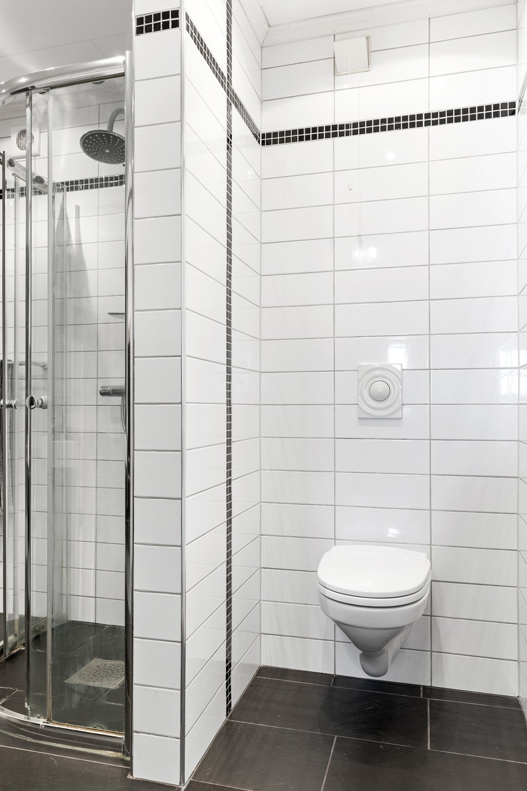 Badet er flislagt på gulv og vegger. Det er vegghengt WC. Galleribilde