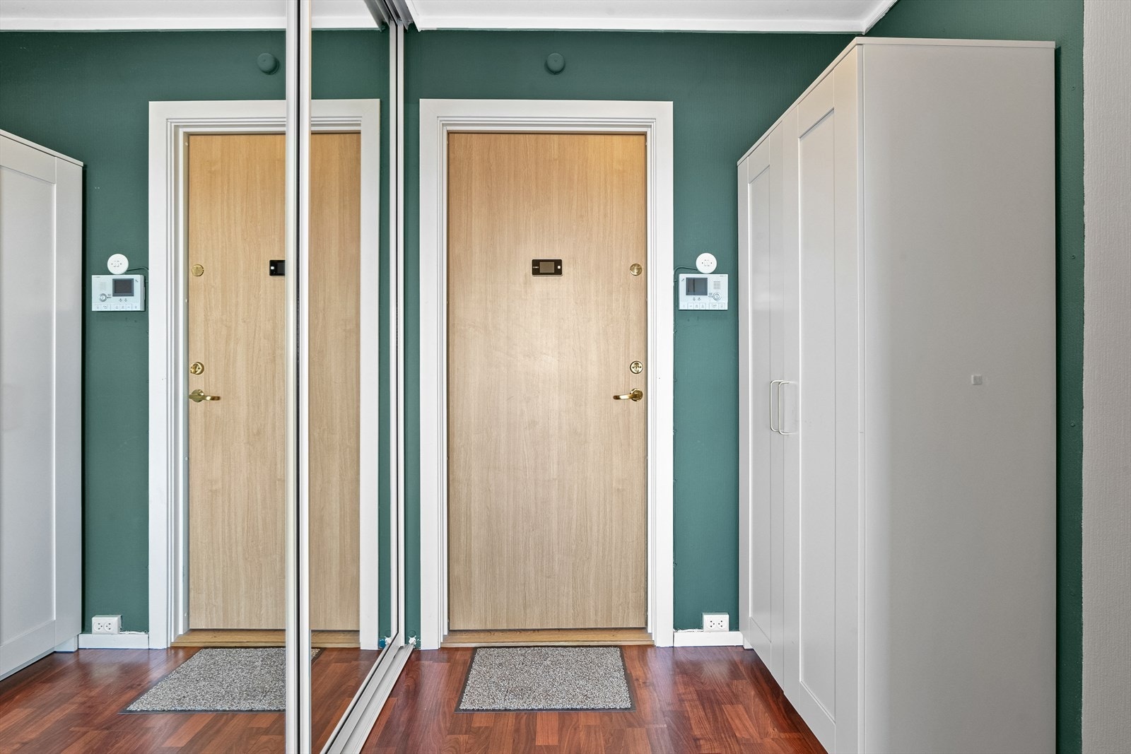 Entré med plass for yttertøy og sko i skap og skyvedører med speilfronter inn til garderoberom. Galleribilde