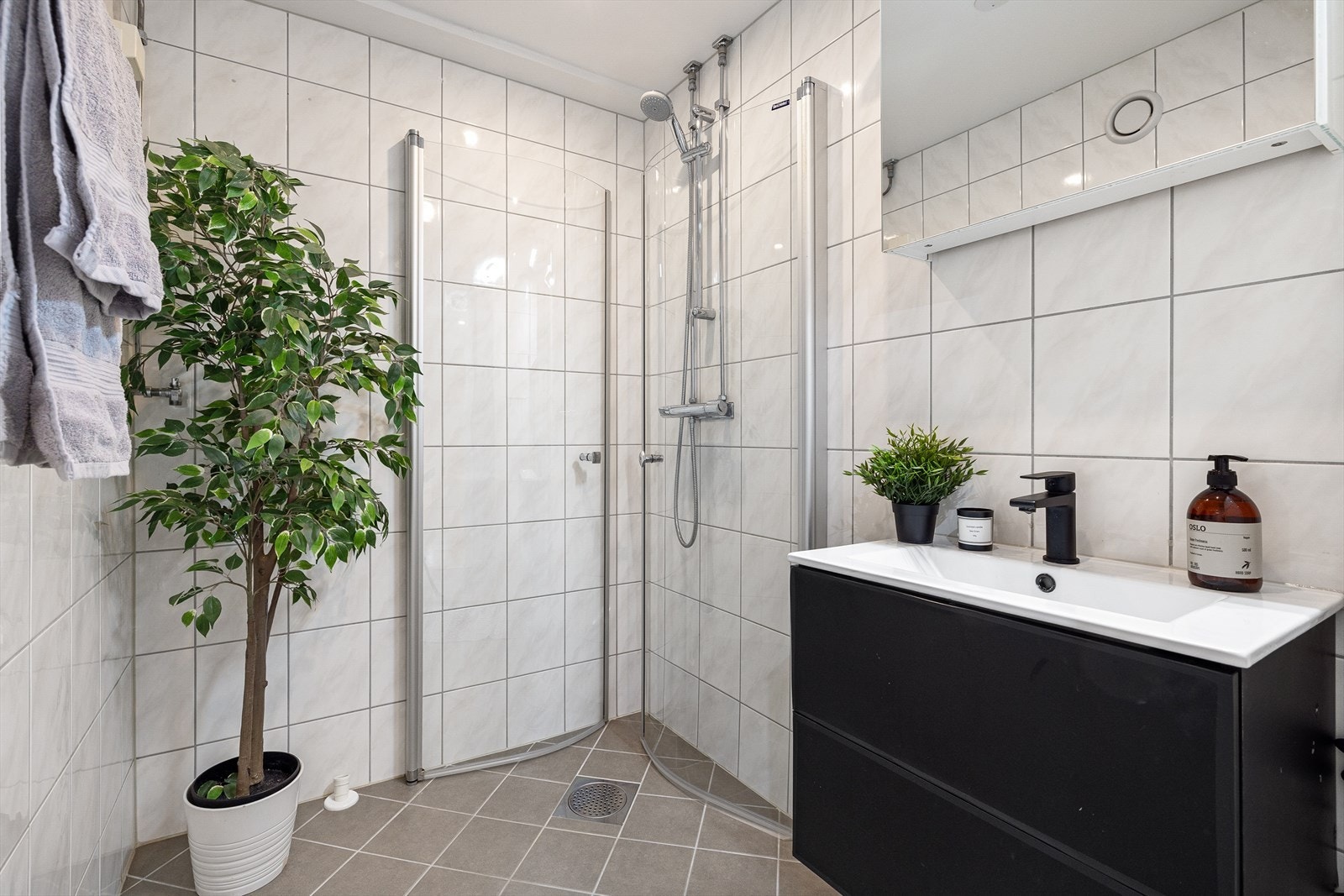 Badet er innredet med baderomsinnredning med speilskap fra 2021 og dusjhjørne med innfellbare glassdører Galleribilde