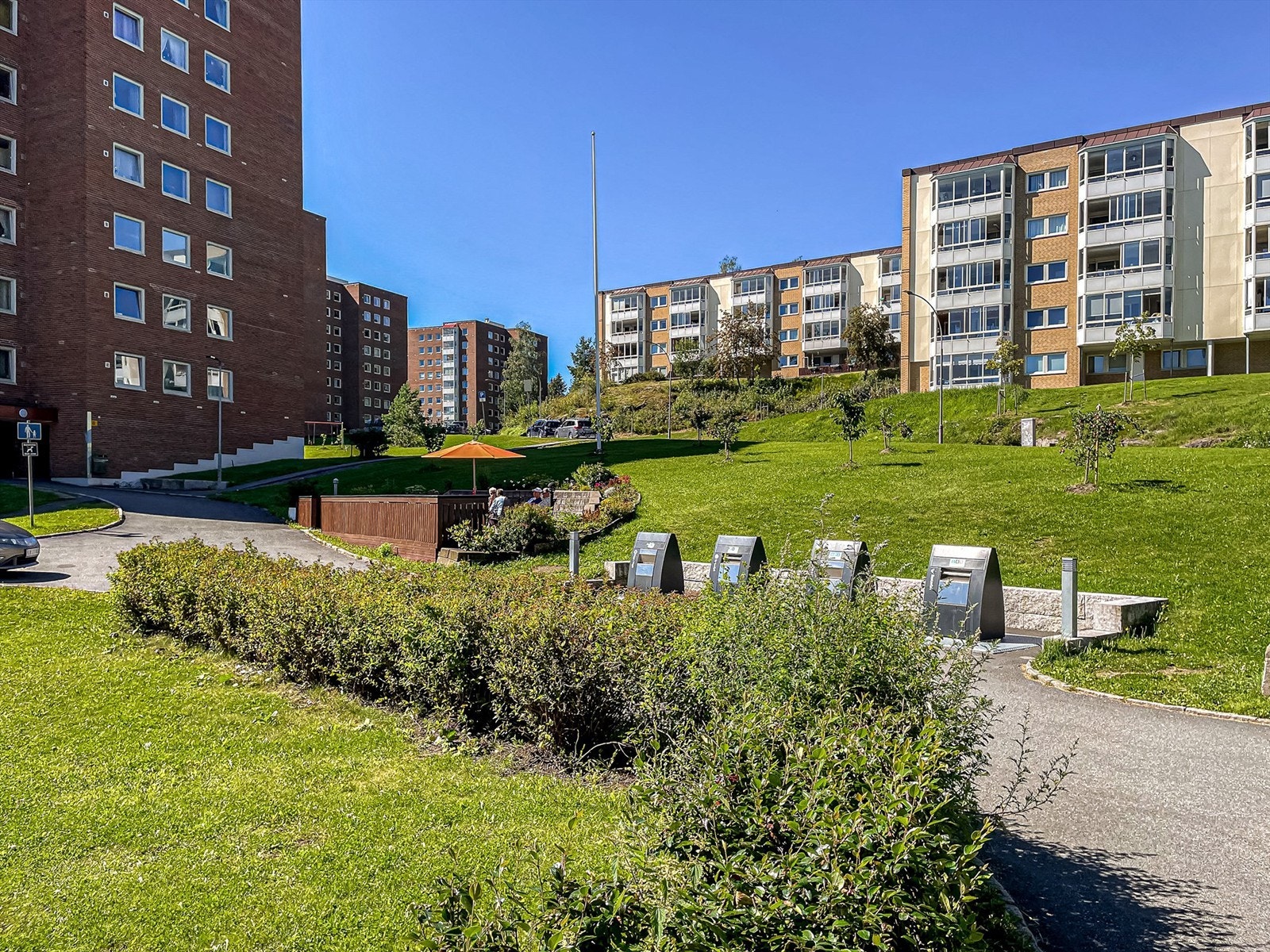 Felles tomt for borettslaget opparbeidet med asfalterte internveier, platting, benker, gressplen, trær hekker og diverse beplantning. Galleribilde