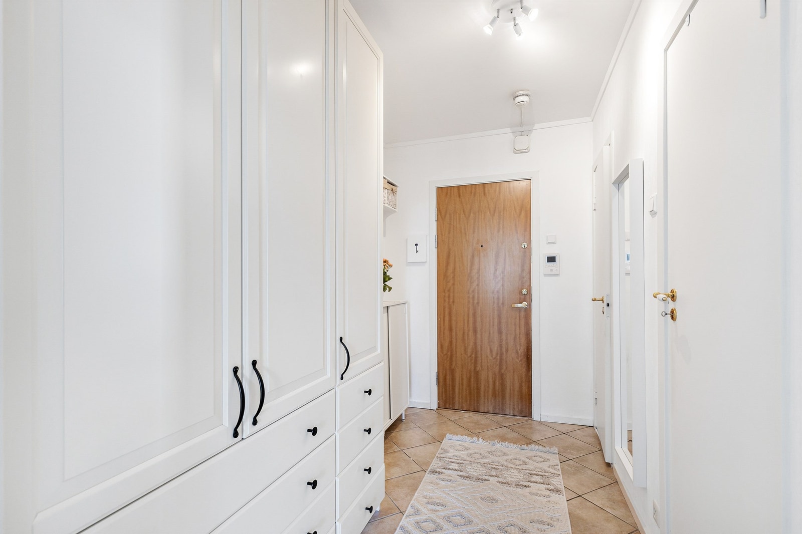 Velkommen inn! Leilighetens entré er lys og innbydende og gir et godt førsteinntrykk av boligen. Her er det god plass til å henge fra seg yttertøyet og sette fra seg sko. Galleribilde