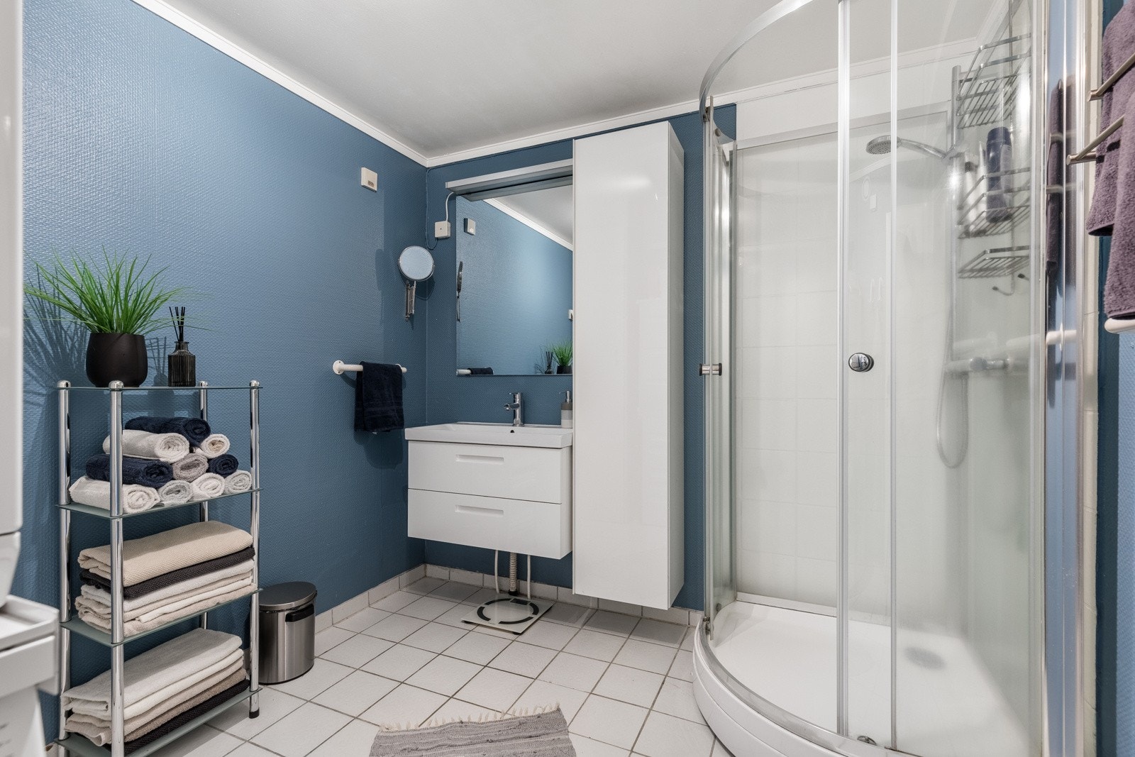 Badet er av eldre dato og er klart for oppgradering, men gir likevel et pent inntrykk med flislagt gulv, blåmalte vegger med fliser i dusjsonen, spotter i himling og gulvvarme. Galleribilde