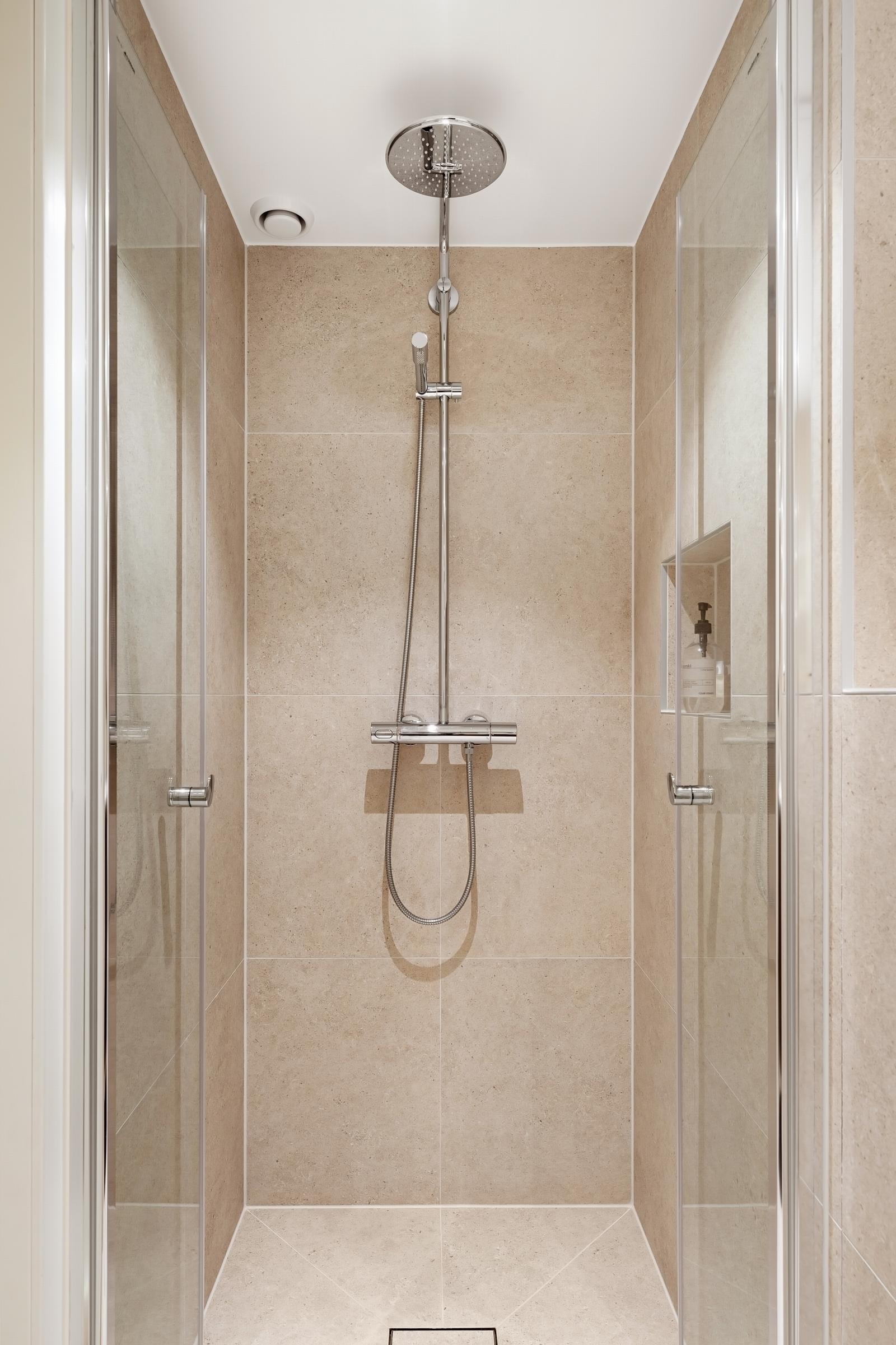 Romslig dusjnisje 90 x 90 cm med regndusj fra Grohe. Lekkert "square tile insert" sluk i dusj, nedsenket fliskant ved dusjdørene Galleribilde