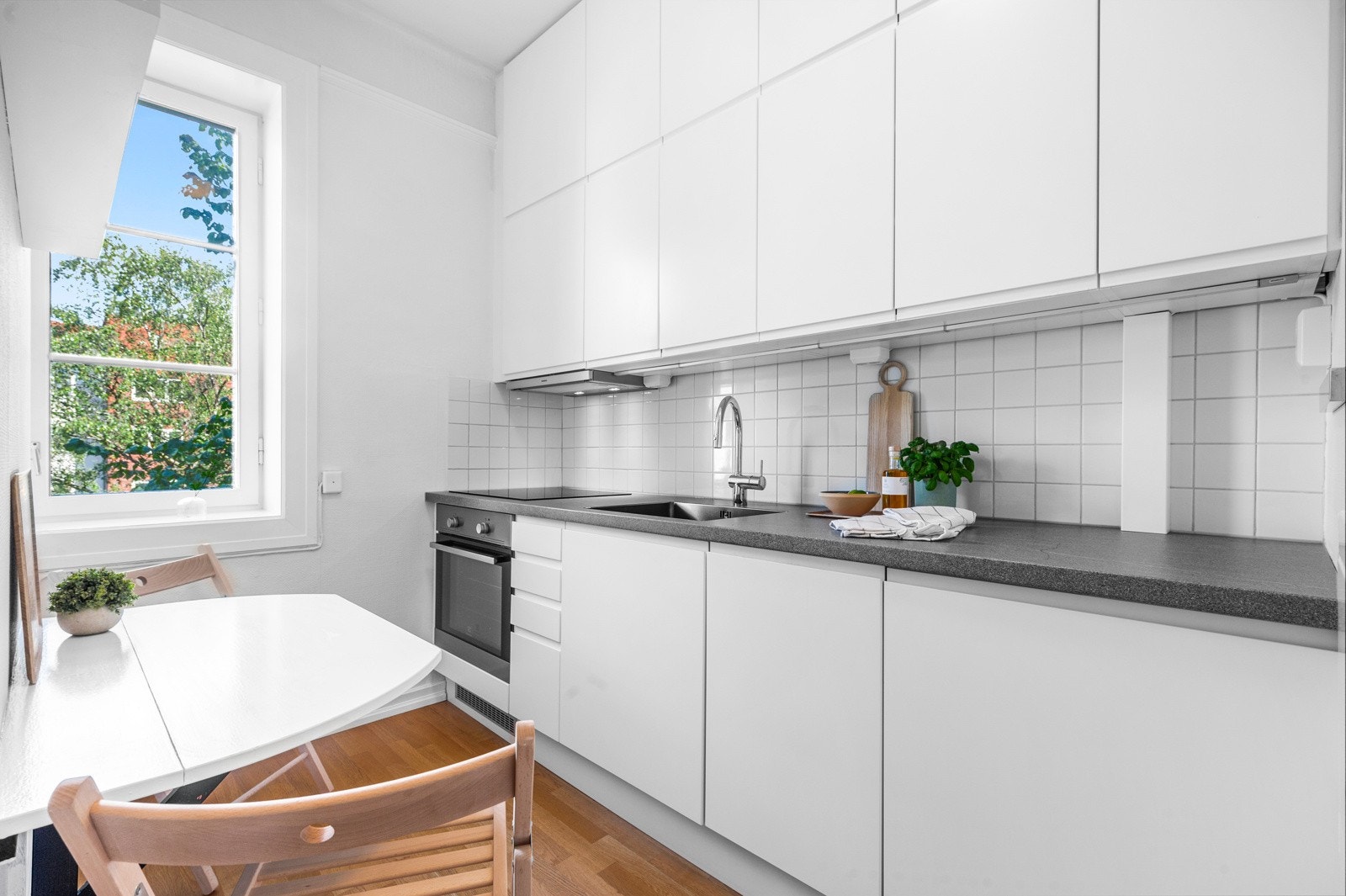 Moderne kjøkken med slette fronter med innfreste håndtak, laminat benkeplate og integrerte hvitevarer. Galleribilde
