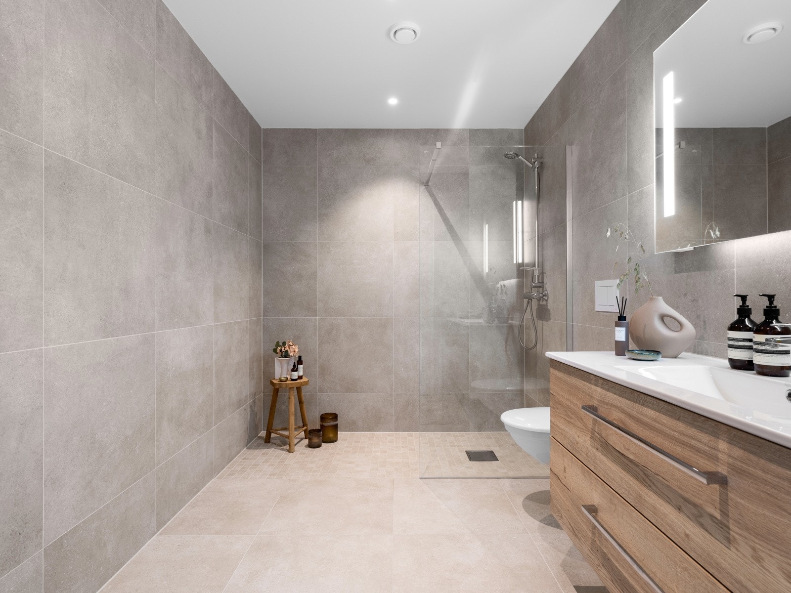 Badet har store, flotte fliser i en moderne farge både på vegger og gulv, samt gulvvarme. Galleribilde