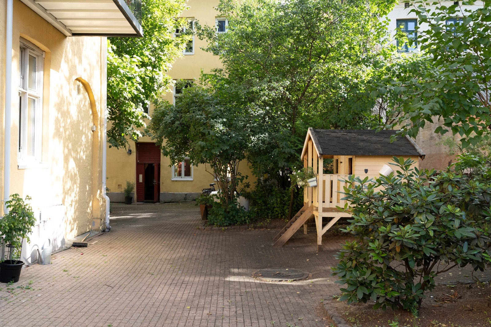Pent opparbeidet bakgård med sittegrupper, trær, sykkelparkering og diverse beplantning. Galleribilde