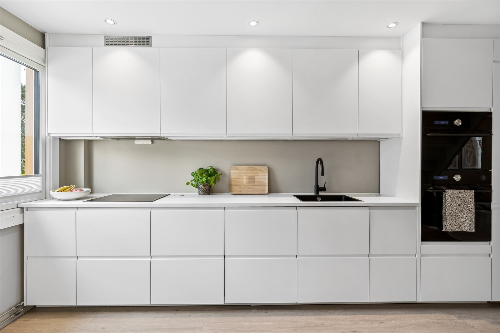 Innredningen har hvite fronter, og lys benkeplate, som matcher fint med veggen bak. Komfyr og mikrobølgeovn er plassert i behagelig høyde. Galleribilde