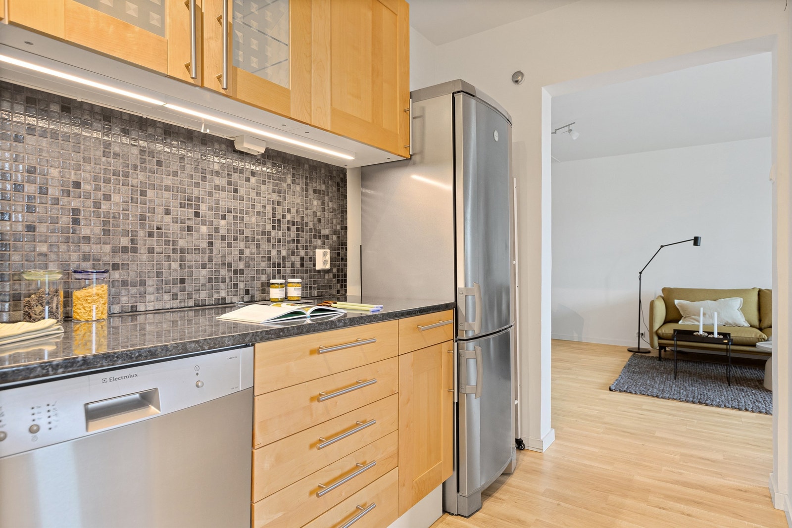 Kjøkkeninnredning med profilerte fronter og benkeplate av laminat. Frittstående kjøleskap med fryser og oppvaskmaskin. Galleribilde