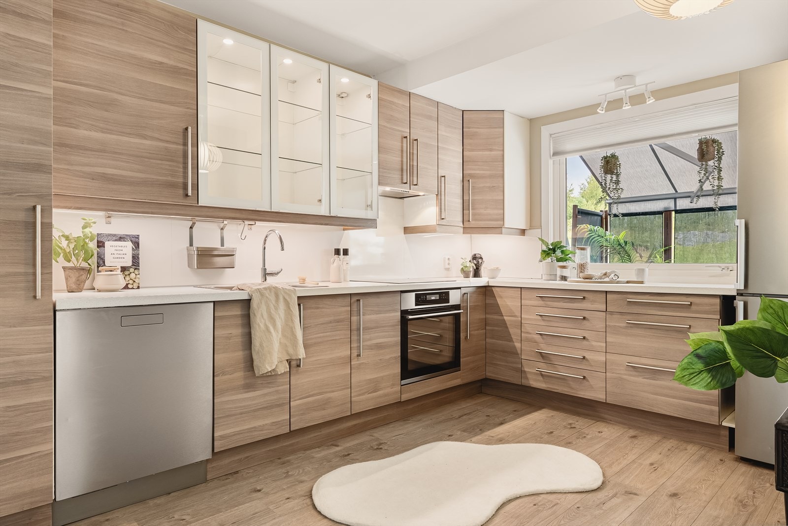 Lekkert og moderne kjøkken utført med slette fronter, to overskap med glassfronter og benkeplate av laminat med nedfelt vask. Galleribilde