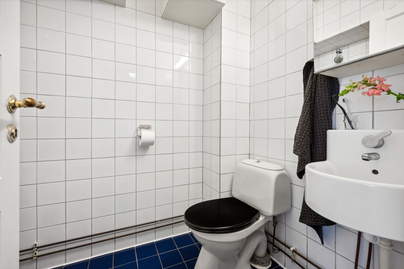 Lyst flislagt bad med wc og enkel baderomsinnredning. Galleribilde