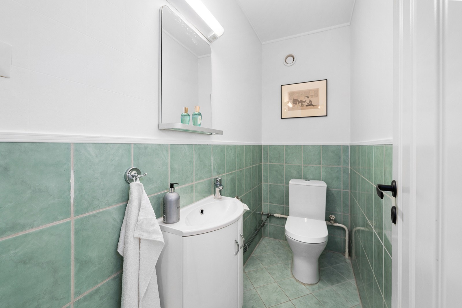 Separat wc-rom med flislagte overflater. Innredningen består av heldekkende servant på underskap, speil og klosett. Galleribilde