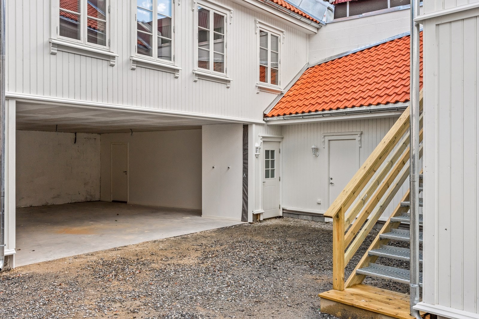 Romslig gårdsplass | Det er garasjeport på eiendommen i dag og hver seksjon vil få tildelt en garasjeplass som følger eiendommen Galleribilde