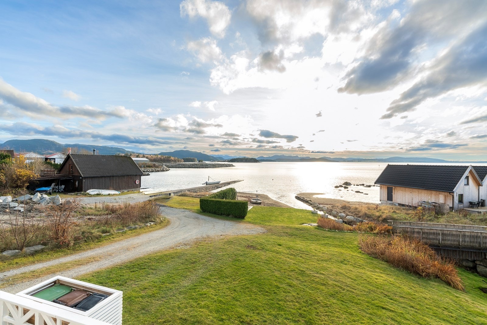 Tomtene er pent opparbeidet med en stor og flott hage, diverse beplantninger, bed, grusete innkjørsel, terrasse og platting nede ved sjøen. Galleribilde