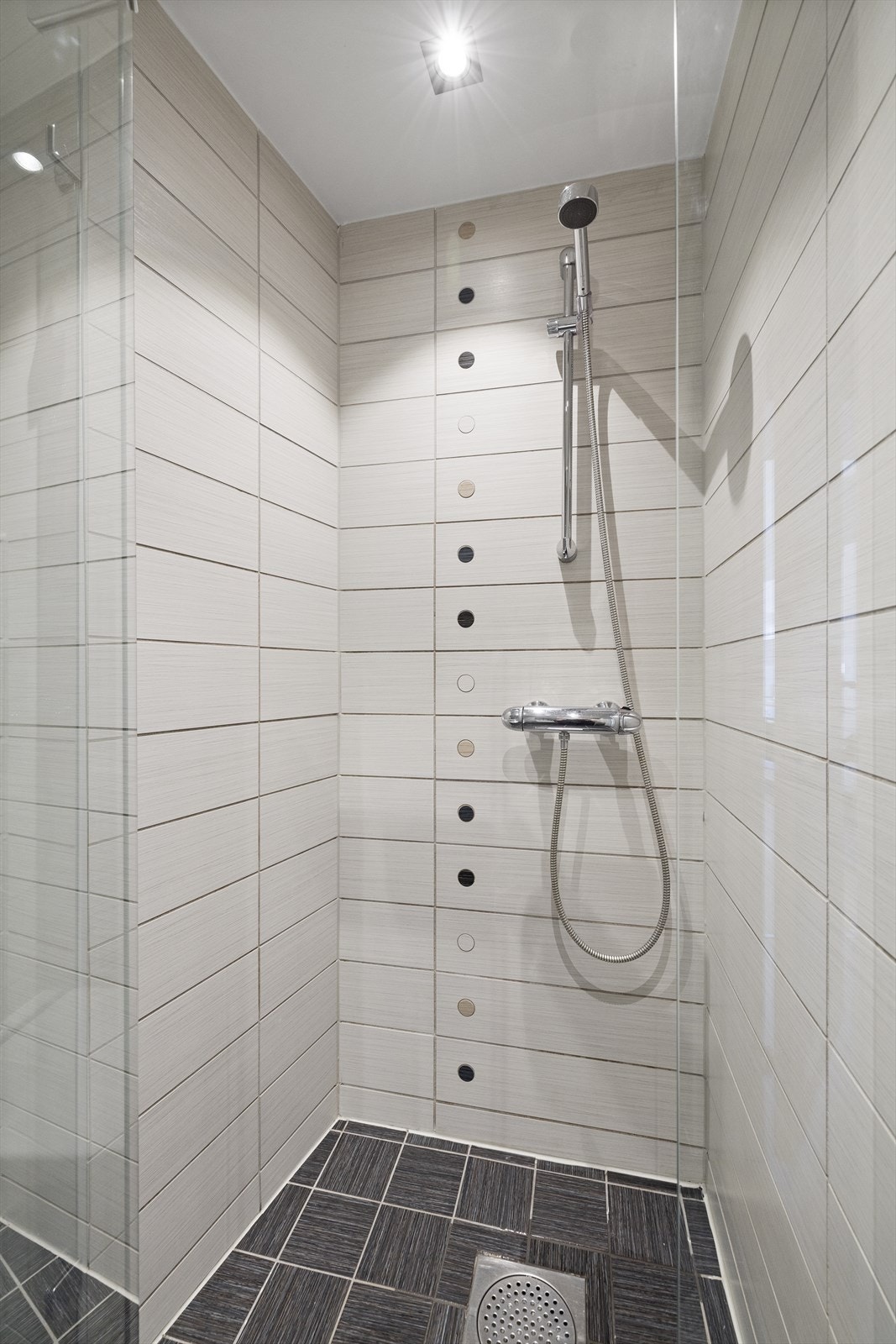 Badet inneholder dusjhjørne med dusjarmatur, veggmontert toalett og servantskap med blandebatteri. Opplegg til vaskemaskin (Zanussi vaskemaskin medfølger) Galleribilde
