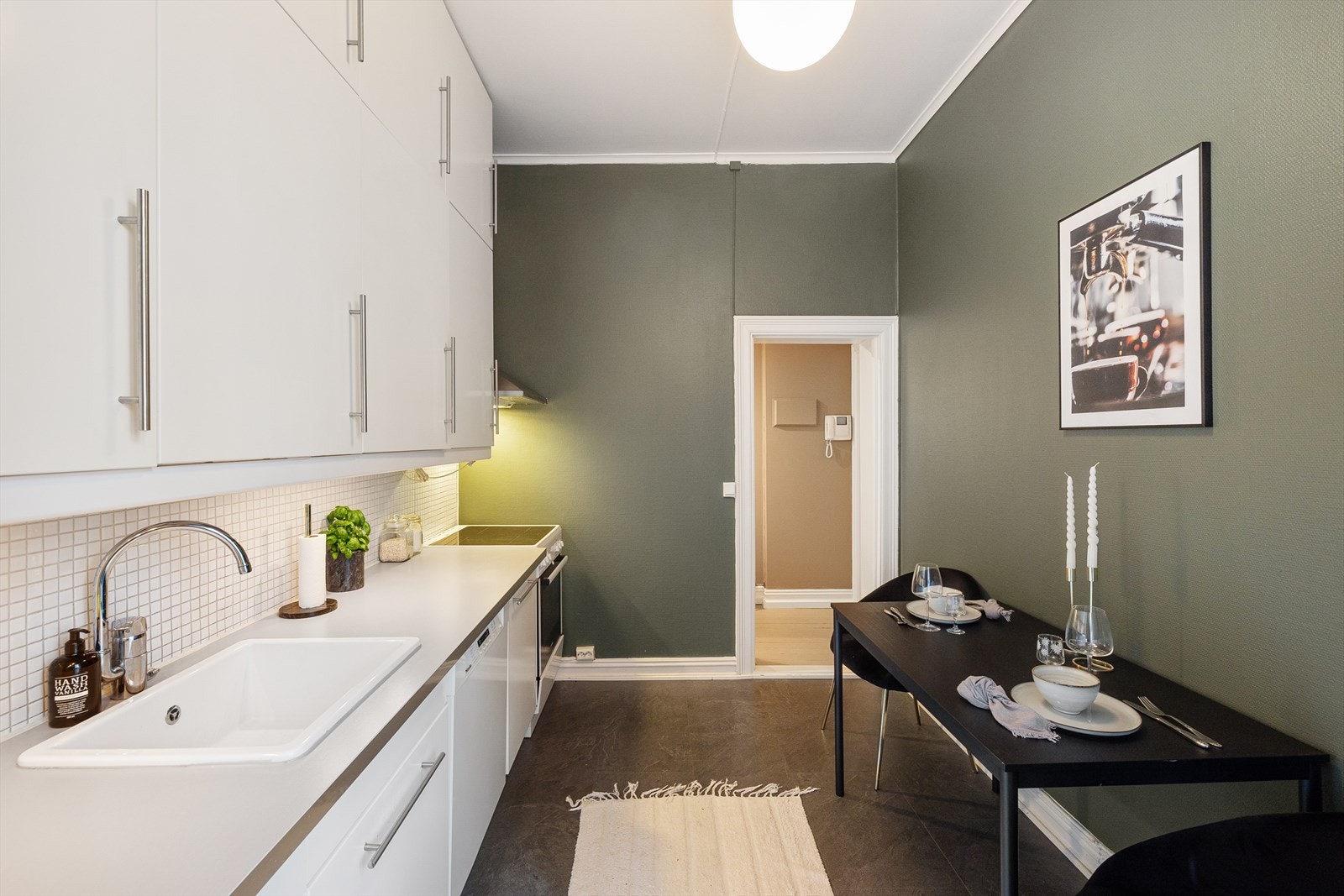 Fliser mellom over- og underskap. Frittstående kjøleskap med fryser, stekeovn, oppvaskmaskin og ventilator over kokesonen. Galleribilde