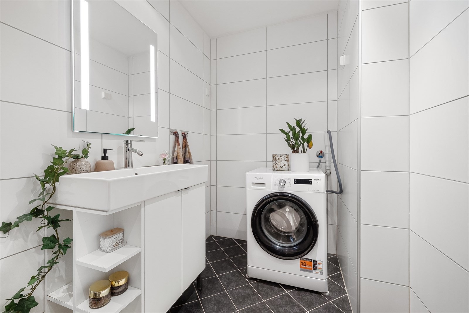 Pent flislagt bad i lyse farger. Det er opplegg for vaskemaskin. Galleribilde