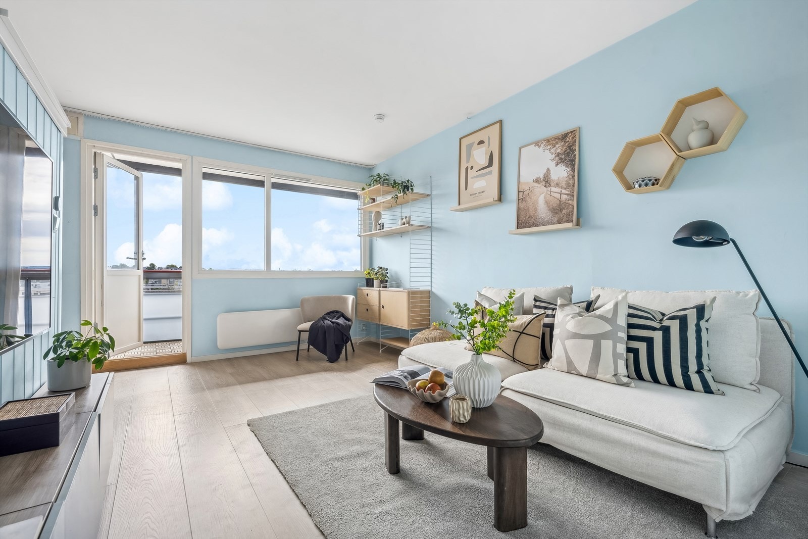 De store vindusflatene fyller leiligheten med dagslys og skaper en åpen og luftig atmosfære Galleribilde