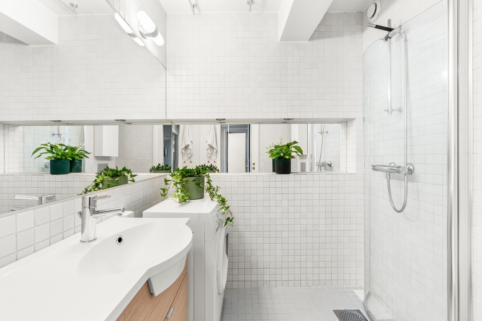 Delikat baderom med hvite mosaikkfliser på vegger og gulv. Galleribilde