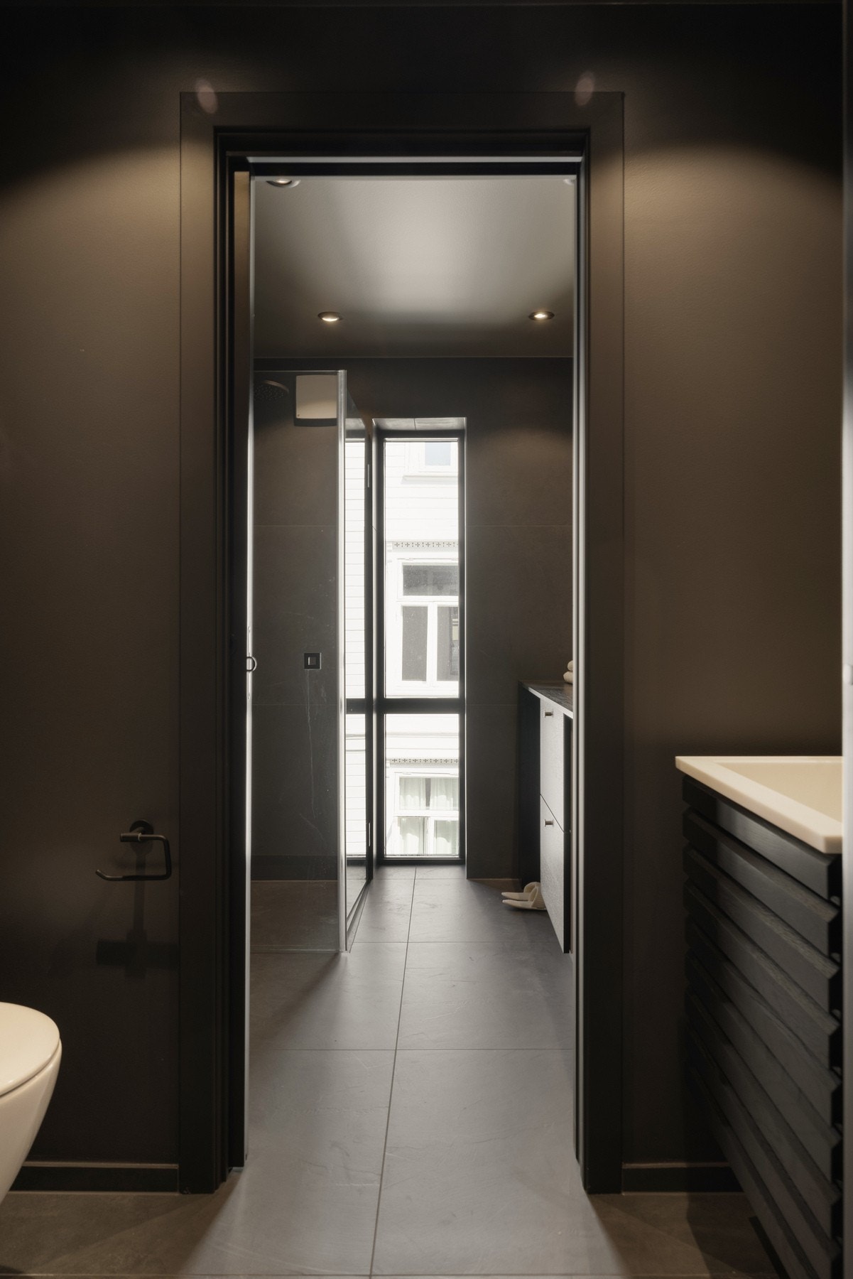 Badet/vaskerommet er innredet med mørke gulvfliser og slette mørke veggflater som gir et rent og moderne uttrykk. Rommet er innredet med toalettdel og baderom-/vaskeromsdel, hvor begge soner er praktisk innredet til sitt formål. Galleribilde