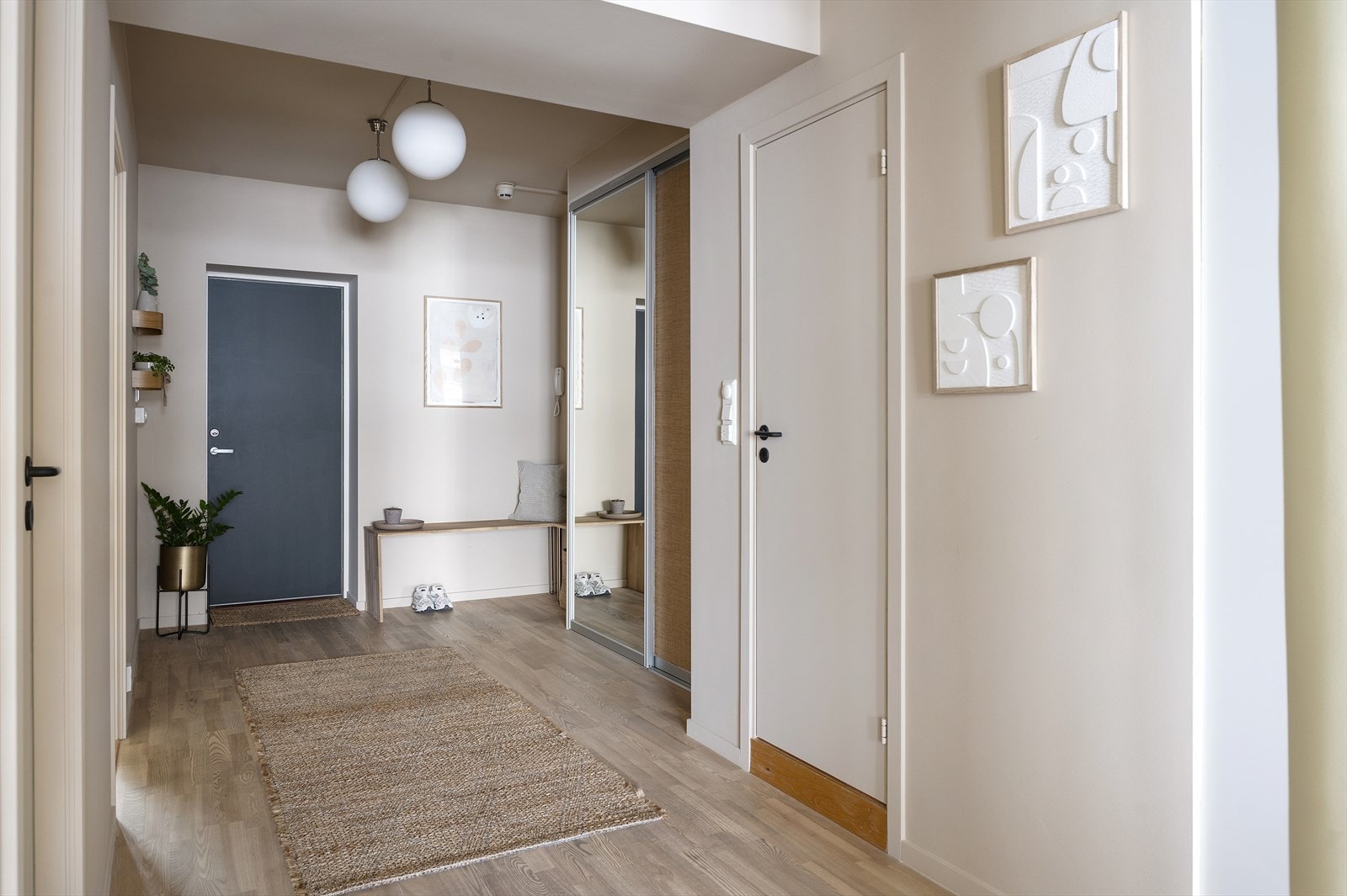 Romslig inngangsparti med praktisk skyvedørsgarderobe med speilfront og knagger for yttertøy og sko Galleribilde
