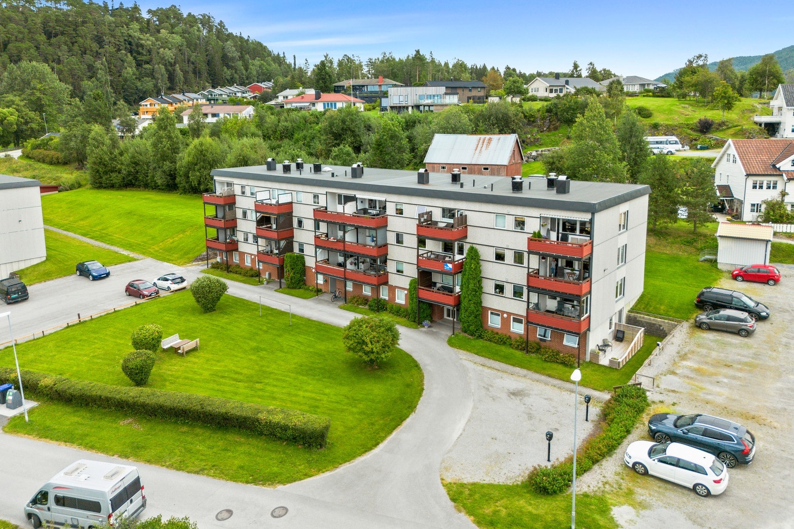 Plenlagt fellesareal med benk. Asfaltert område ved bygget. Galleribilde