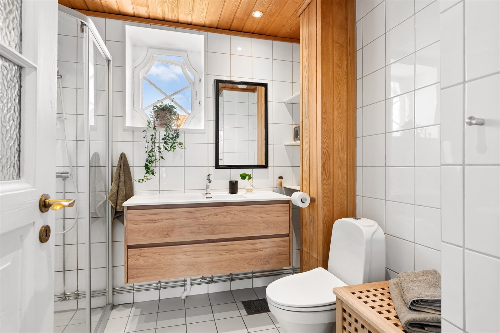 Flislagt baderom med varmekabler, flislagte vegger og trepanel med downlights. Galleribilde