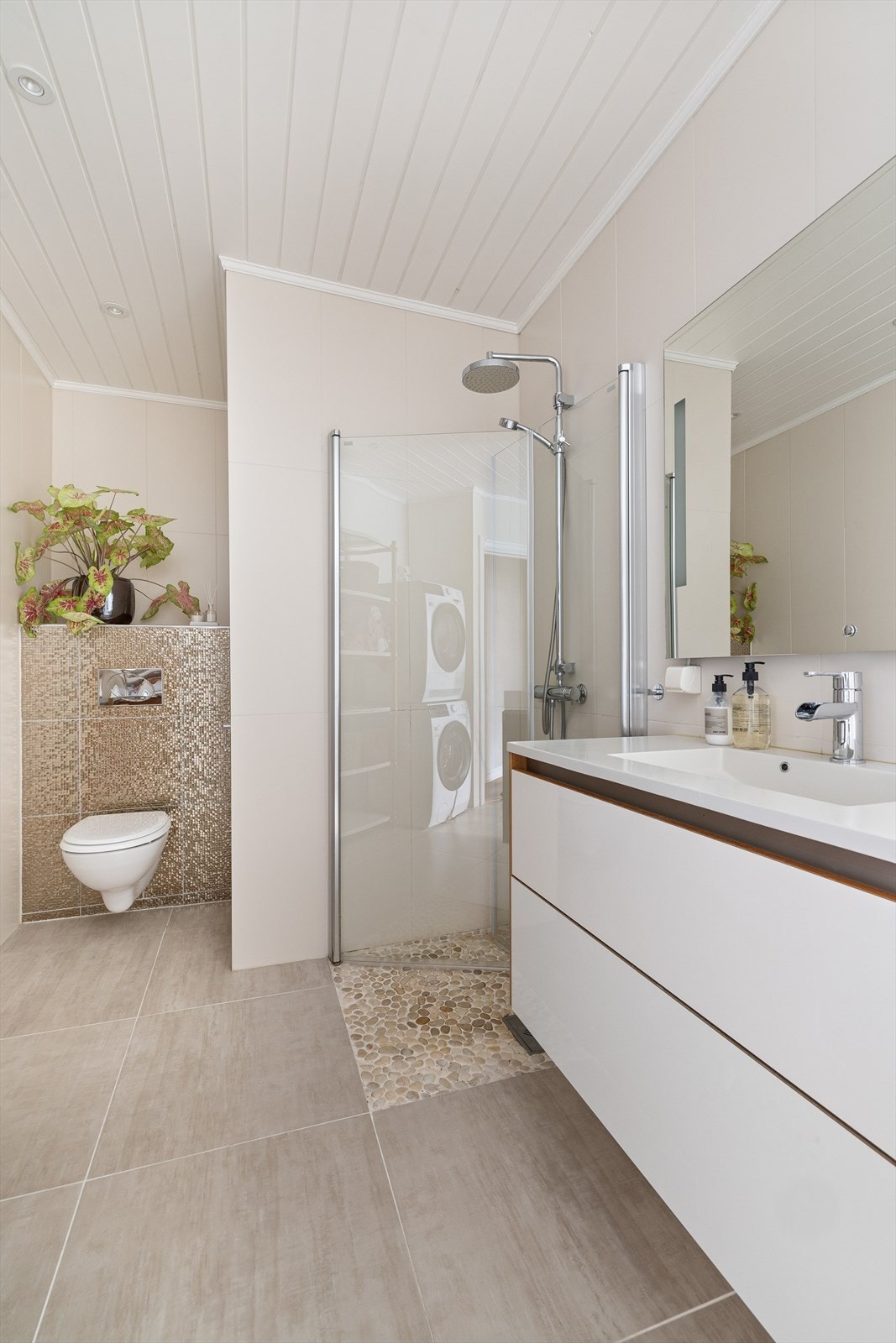 Det er store lyse fliser på både gulv og vegger som er med på å skape en god romfølelse Galleribilde