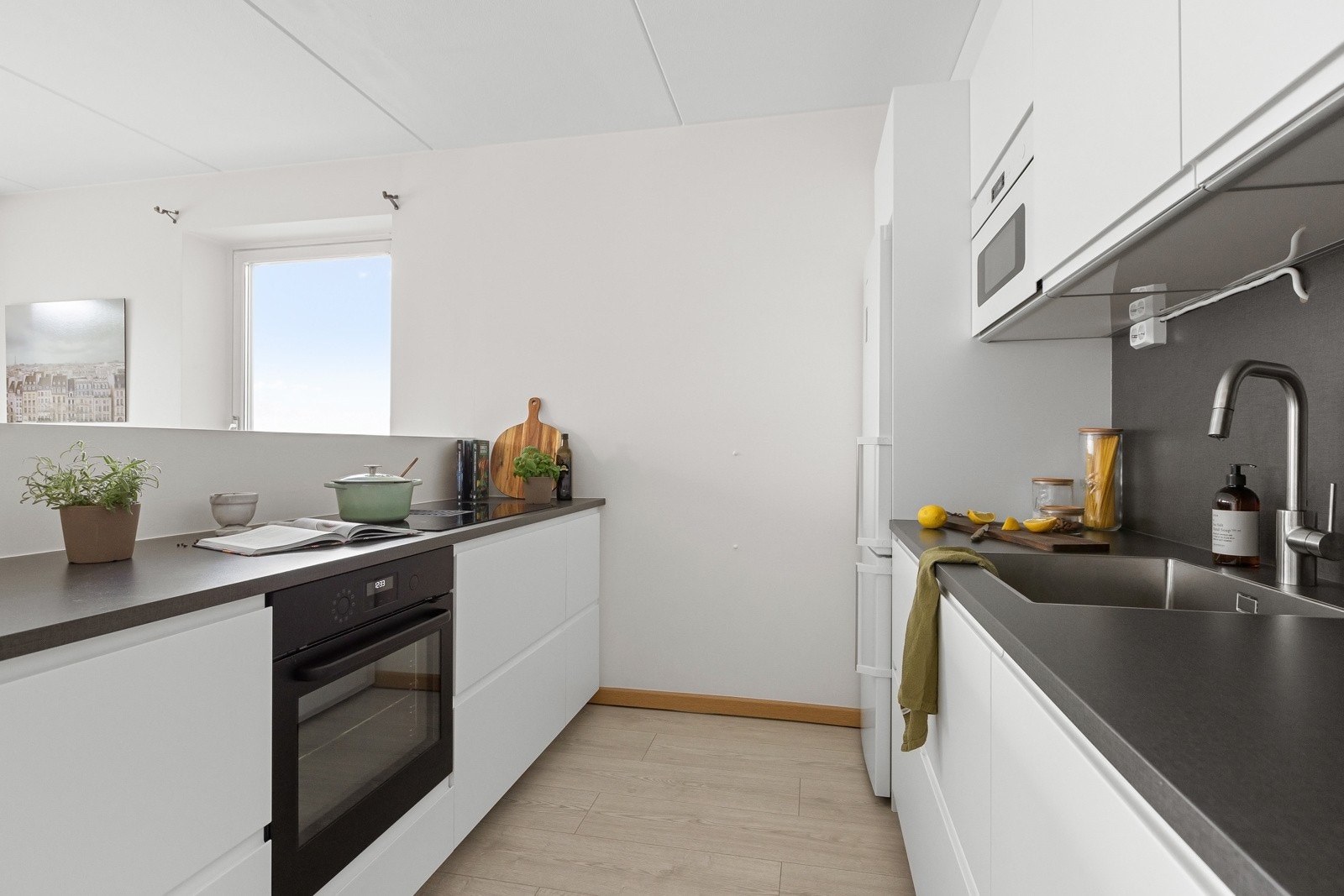 Kjøkkenet fra 2021 er moderne med IKEA-innredning som har slette lakkerte fronter og en solid laminat benkeplate med underlimt oppvaskkum og sprutplate over. Galleribilde