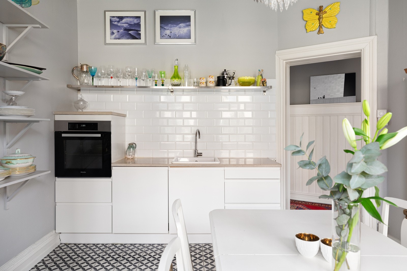 Benkeplate i stein med nedfelt keramisk vask og ett-greps armatur i krom. Integrerte hvitevarer som oppvaskmaskin fra Bosch og stekeovn fra Miele Galleribilde