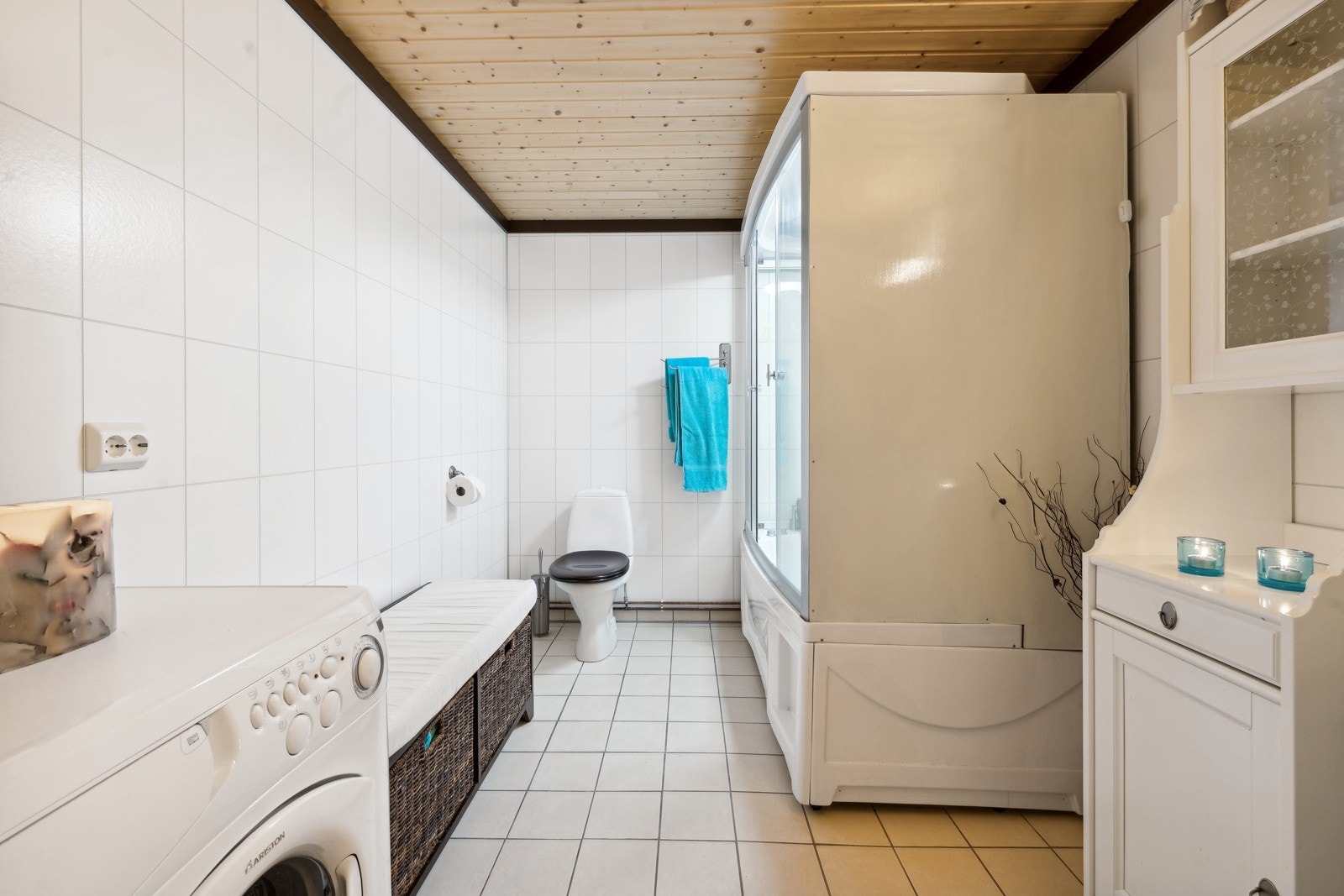 Romslig bad, med flis på gulv, og opplegg for vaskemaskin. Galleribilde