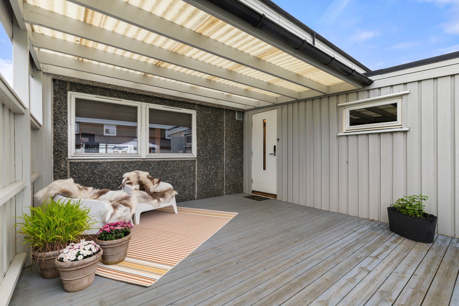 Boligen har terrasse på begge sider av boligen. Takoverbygg ved inngangsparti. Galleribilde