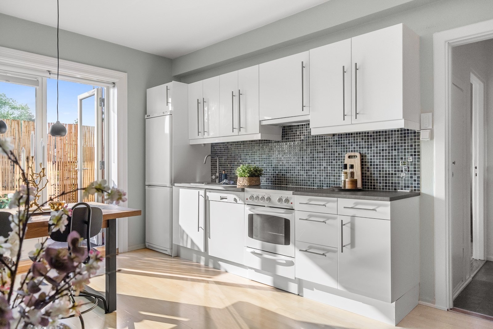 Moderne IKEA-kjøkken med god skap- og benkeplass. Kjøkkenet har høyglansede fronter, laminatbenkeplate med nedfelt kum i rustfritt stål, belysning under overskapene, samt fliser på veggen over benken. Galleribilde