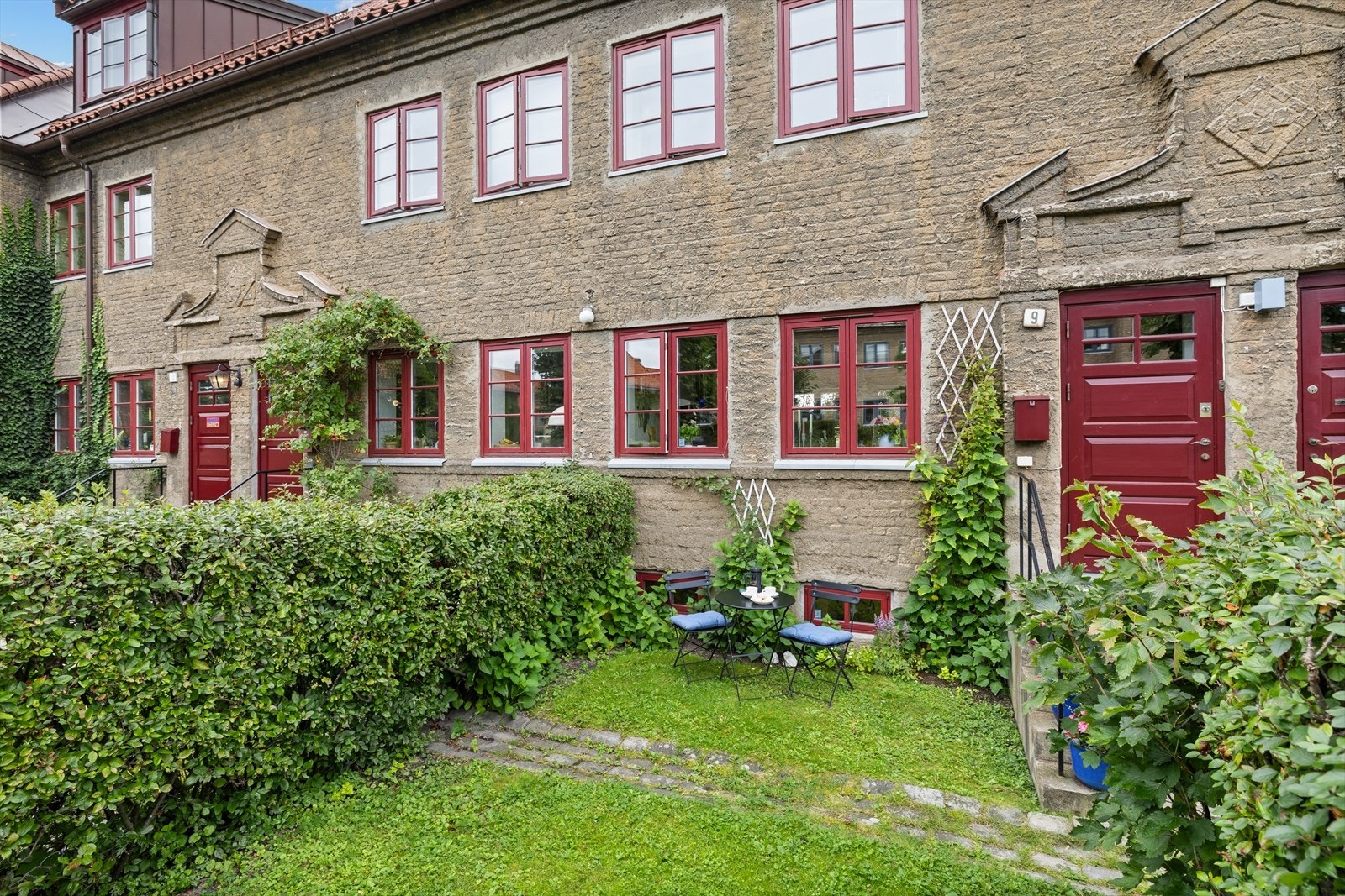 Plen, hekk og gress på uteplassen ved inngangen. Galleribilde