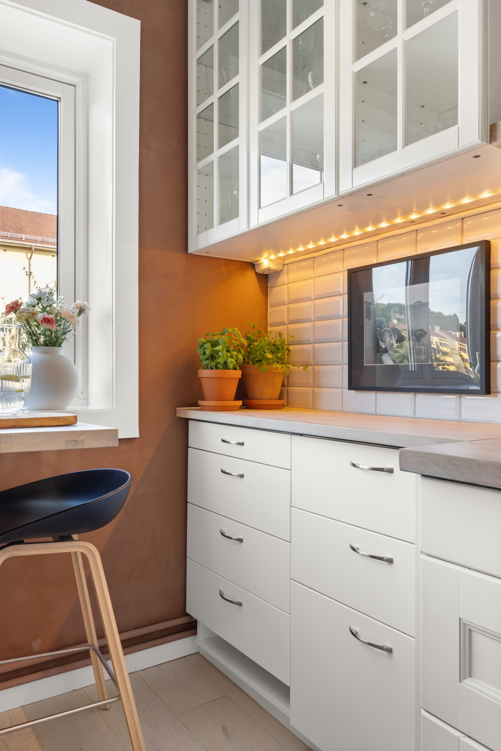 Hvite, profilerte fronter og fliser over benkeplate av tre, i tillegg til belysning over benk. Galleribilde