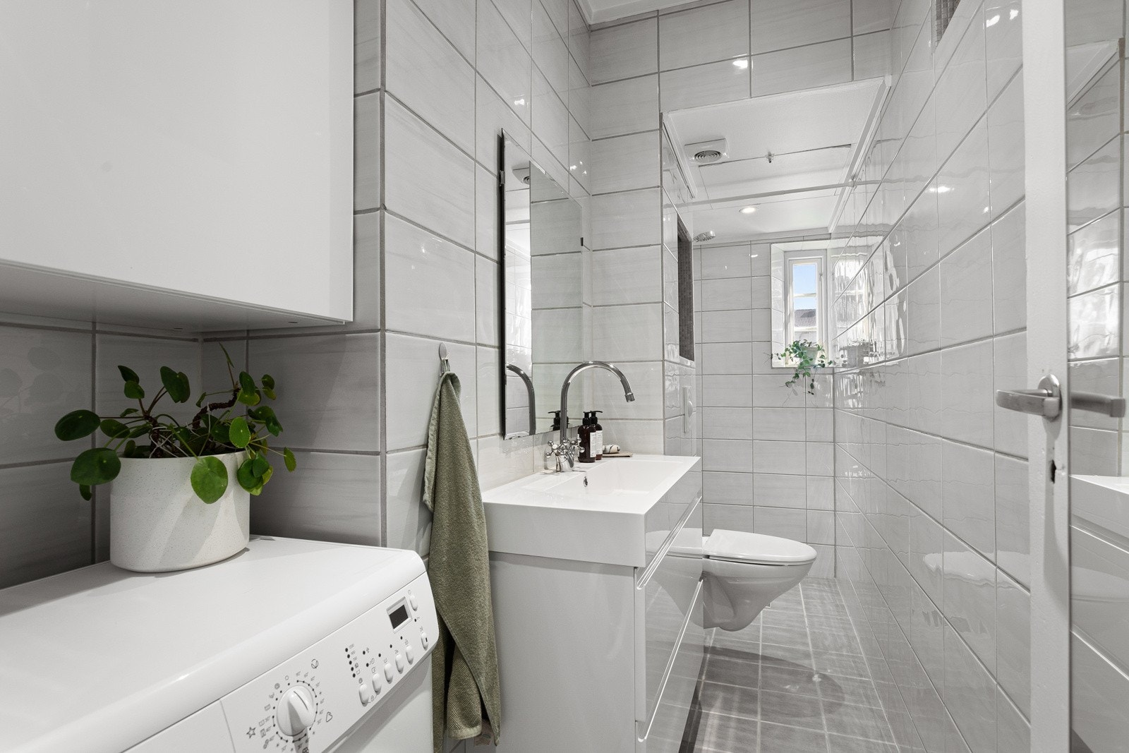 Moderne baderomsinnredning med skuffer og heldekkende servant, vegghengt speil over. Galleribilde