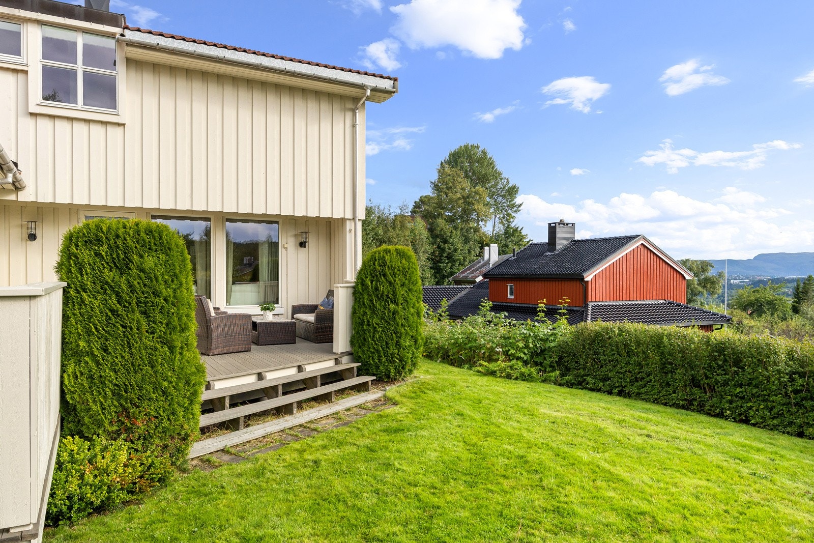 Trapp fra terrasse ned til hage som omkranser boligen på tre sider. Galleribilde