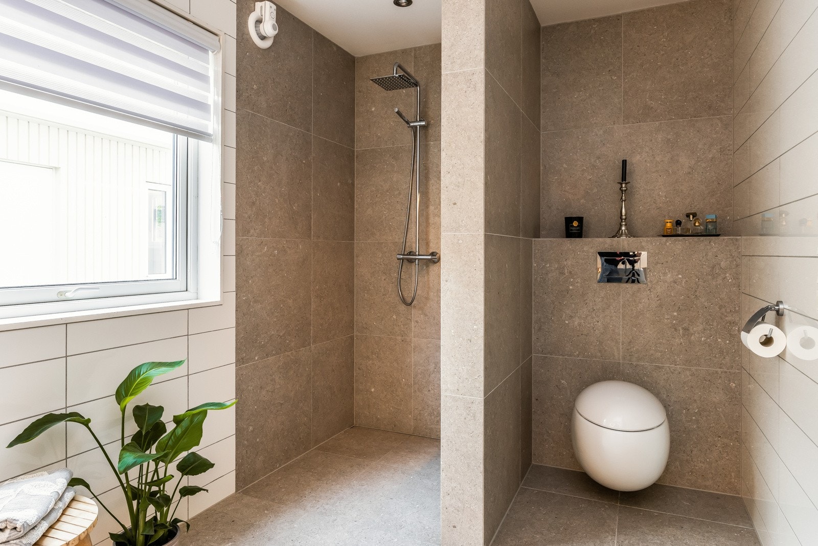 Badet har fliser på vegger og gulv (60x60 fliser) og er utstyrt med baderomsinnredning fra Fossline med dobbel servant, vegghengt toalett fra Alessi og romslig dusjnisje. Galleribilde