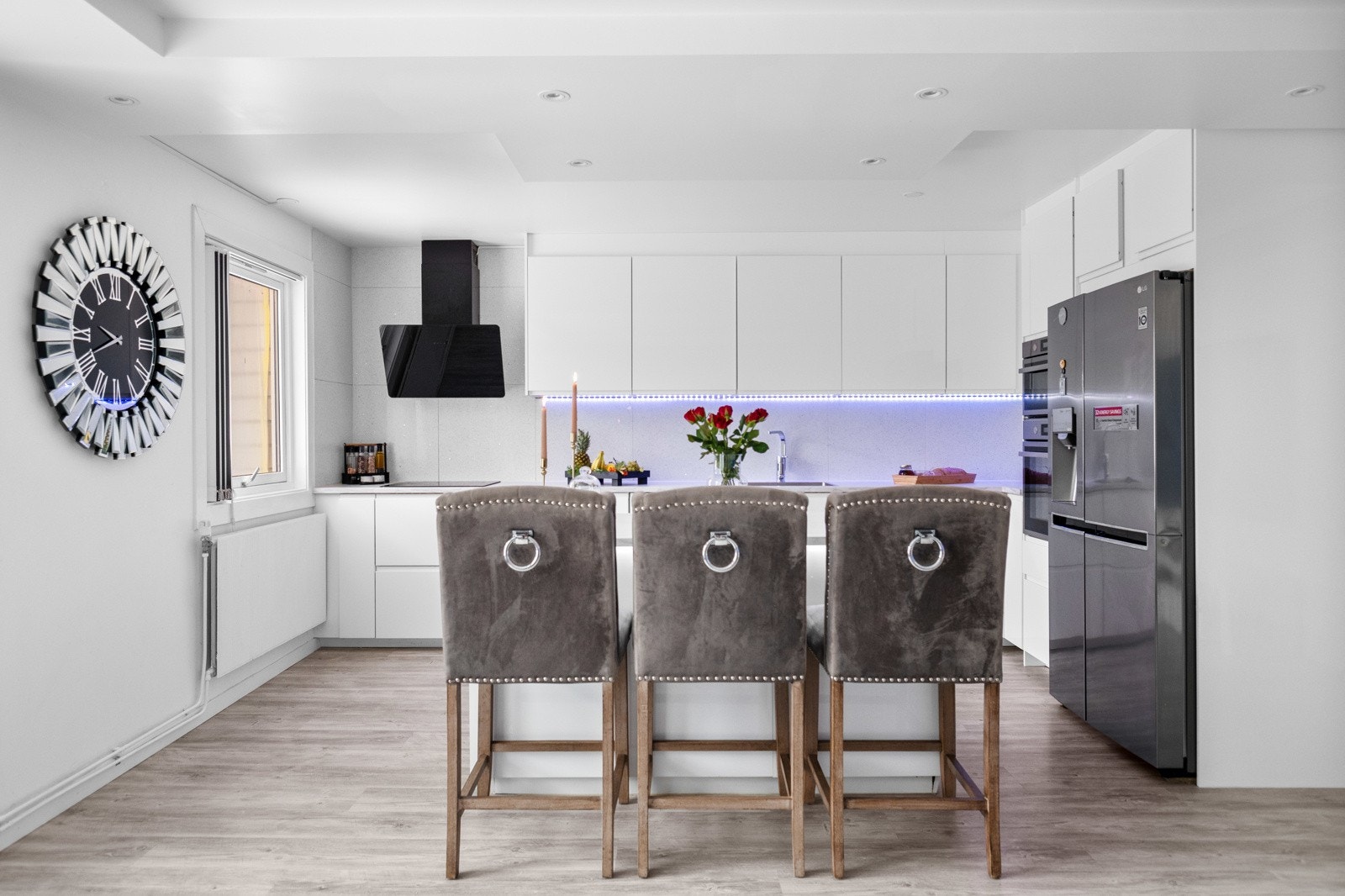 Kjøkkenets rene linjer og moderne løsninger sklir sømløst inn i det hvite, stilfulle allrommet. Galleribilde