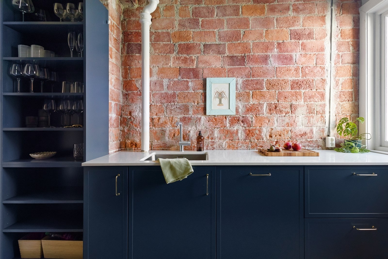 Innredningen har en nydelig dyp blå fargetone som kombineres perfekt med den rustikke, originale teglstensveggen Galleribilde
