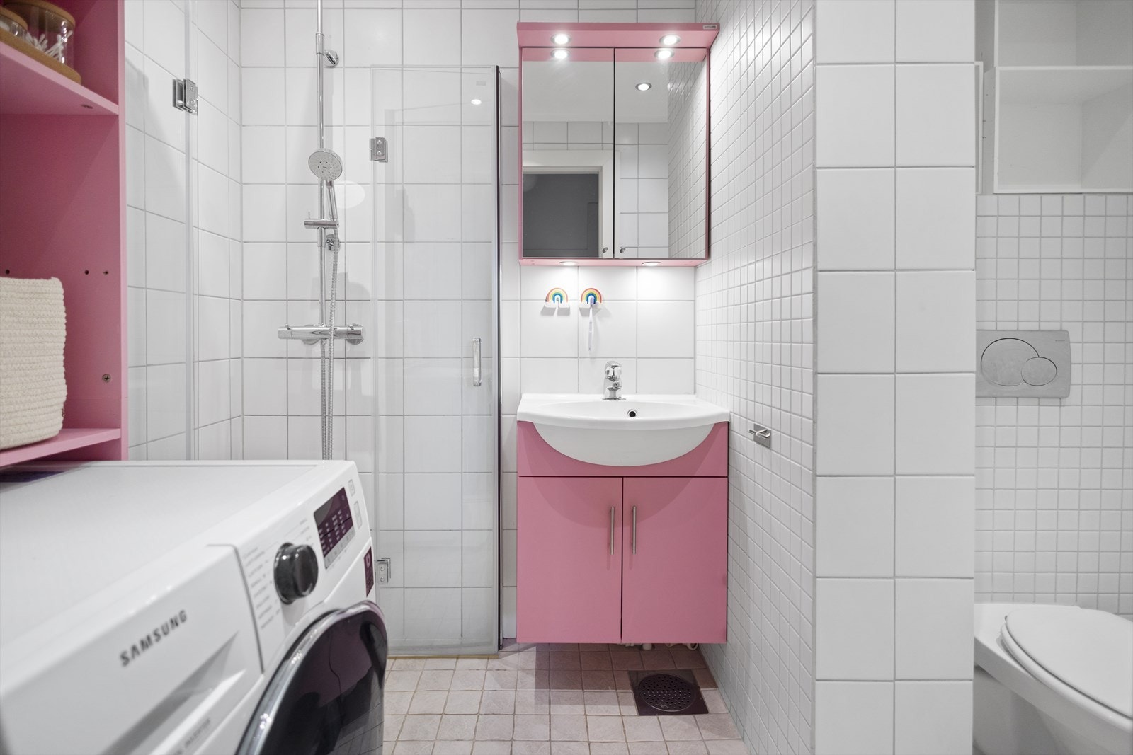 Pent, flislagt baderom med varmekabler i gulv som gir behagelig varme. Badet har god oppbevaringsplass i speilskap samt i skapinnredning under servant. Det er i tillegg en praktisk hylleløsning over vaskemaskin som rommer mye. Galleribilde