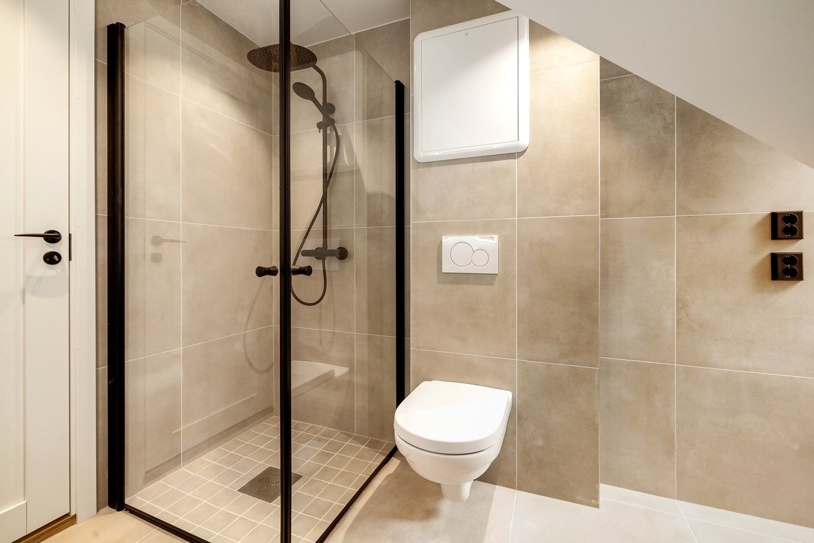 Badet inneholder vegghengt toalett, helstøpt servant, skuffer under servant med slette fronter, dusjdører i klart glass og opplegg for vaskemaskin. Galleribilde