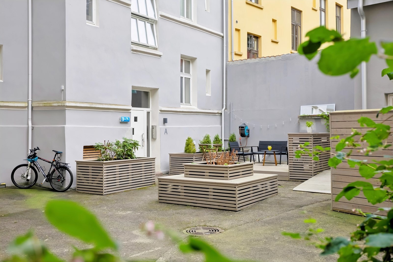 Pent opparbeidet bakgård med blomsterkasser og sittegrupper. Galleribilde