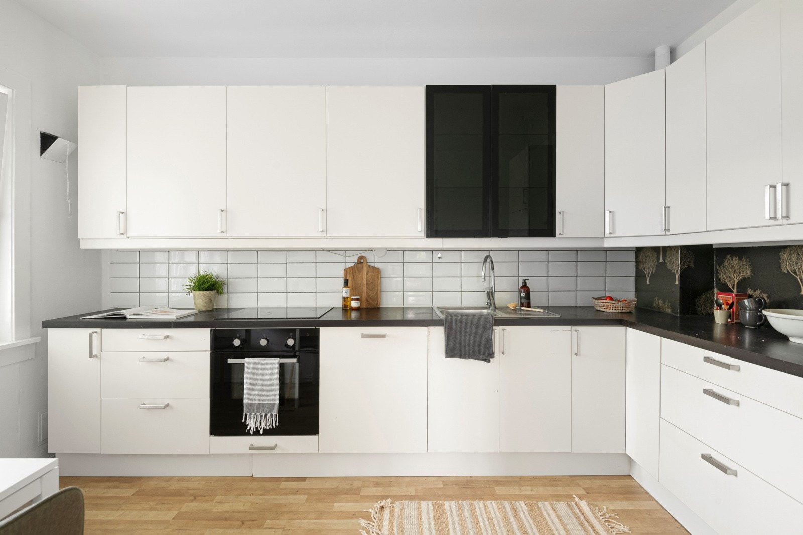 Kjøkkeninnredning(2011) i lyse, glatte fronter fra IKEA med laminat benkeplate, oppvaskkum og fliser over kjøkkenbenk samt lys under overskap. Integrert komfyr med keramisk platetopp, integrert oppvaskmaskin og integrert kjøl- og fryseskap. Galleribilde