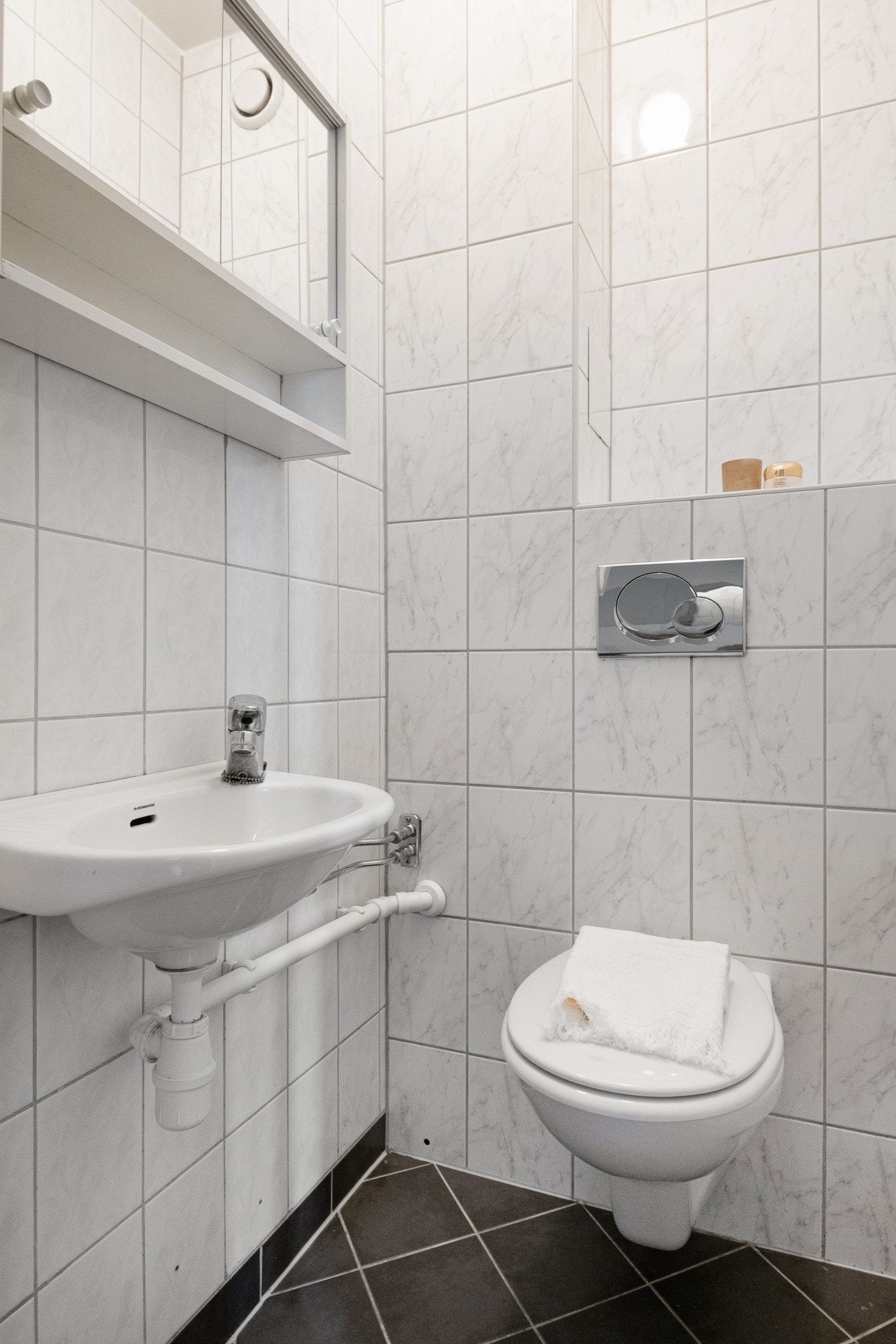 Separat toalett med inngang fra entréen er praktisk tilgjengelig for gjester. Toalettet er flislagt og innehar servant, speilskap og veggmontert toalett. Galleribilde