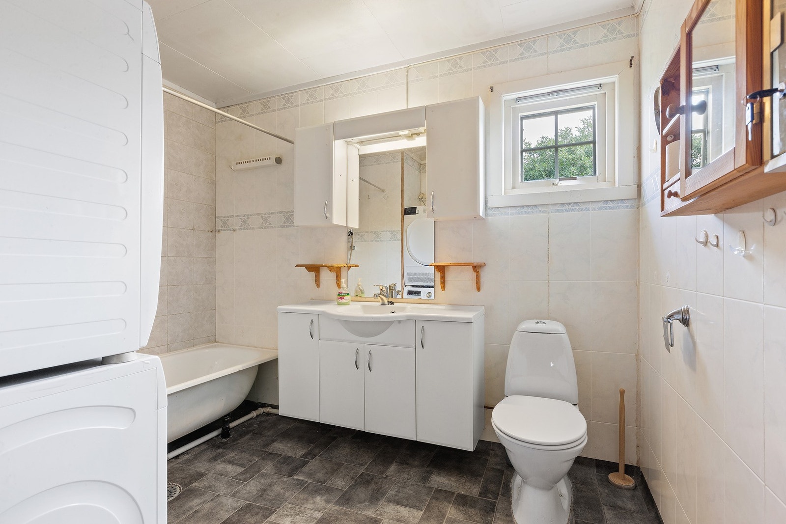 Badet har lys innredning med nedfelt servant og skap under, overskap og speil med lys over, badekar, toalett og opplegg for vaskemaskin. Varme i gulv Galleribilde