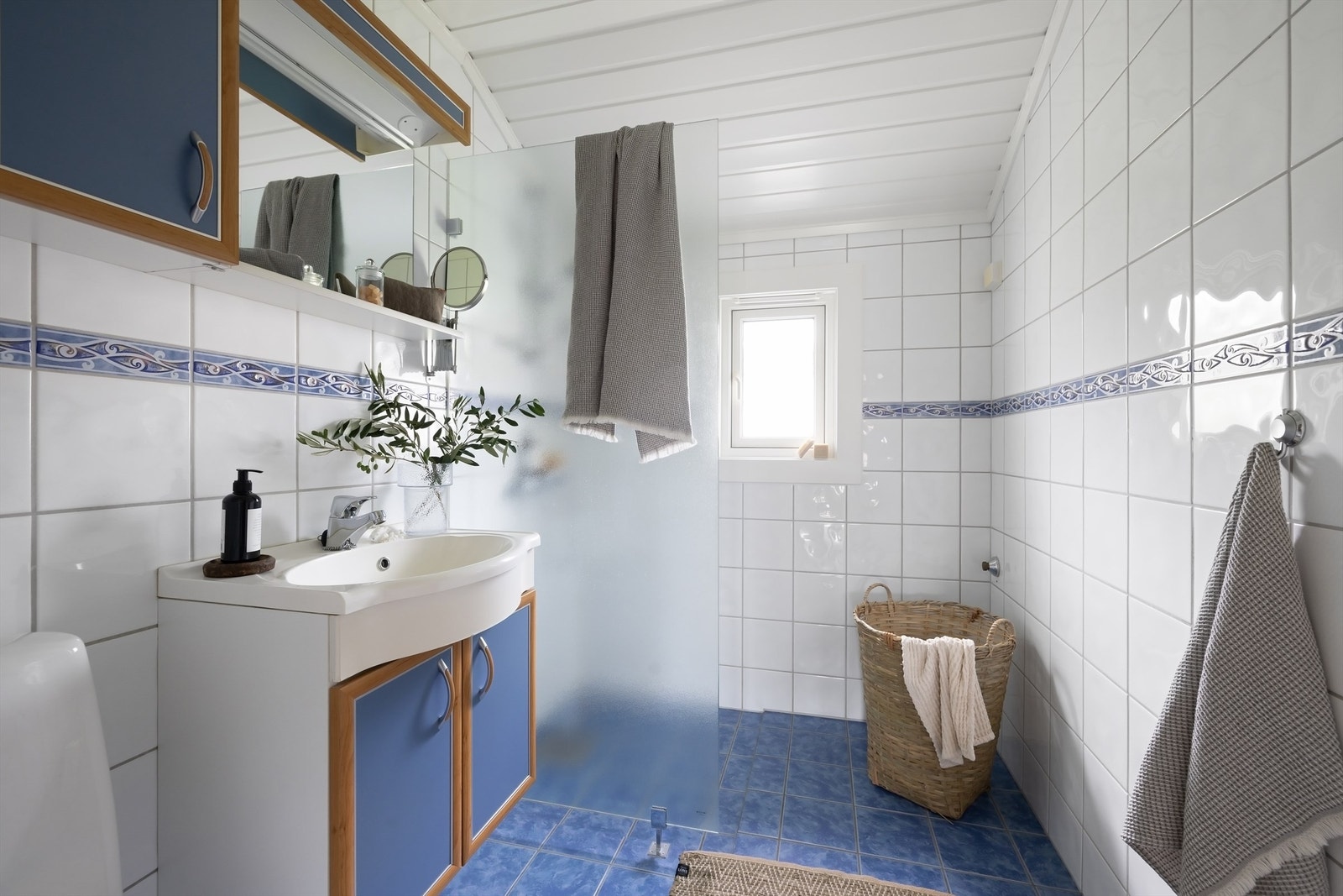 Badet har vegghengt servantskap med servant. Over servanten er det skap for oppbevaring, speil og belysning Galleribilde