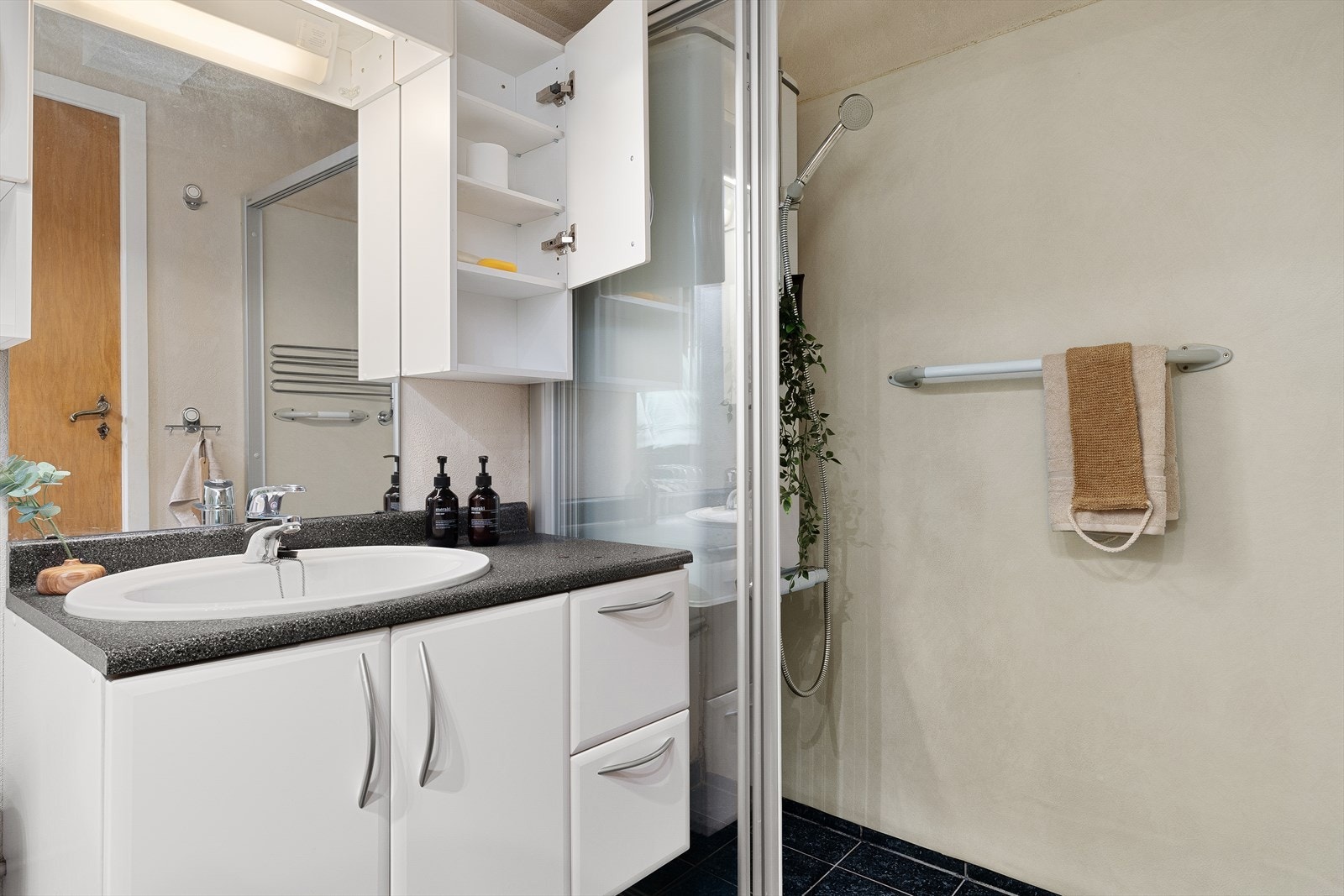 Innredet med dusjhjørne og skyvedør, servant med skap og speil samt toalett. Galleribilde