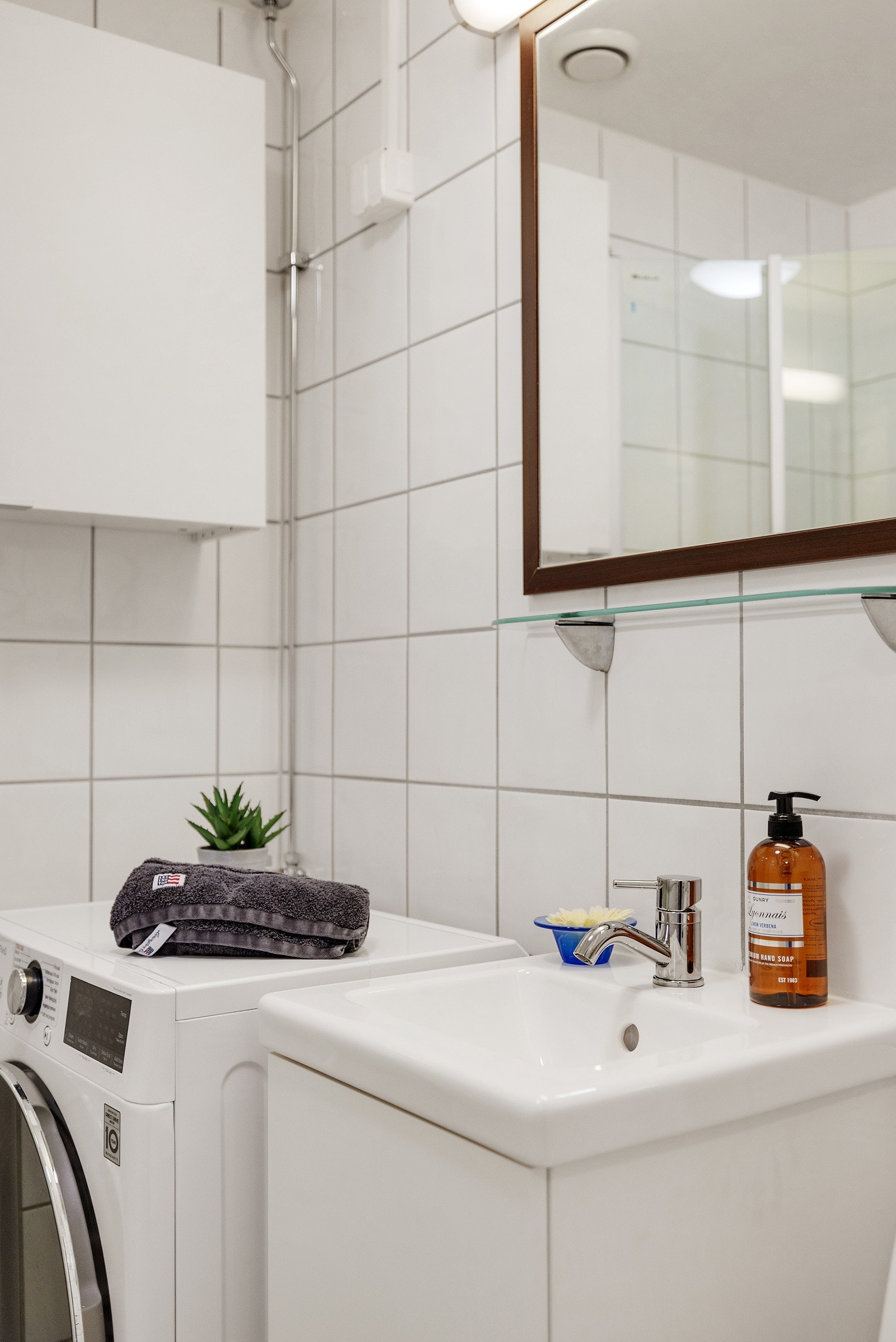 Det er servant på vegghengt servantskap fra 2024 og vegghengte dusjdører i glass. Galleribilde